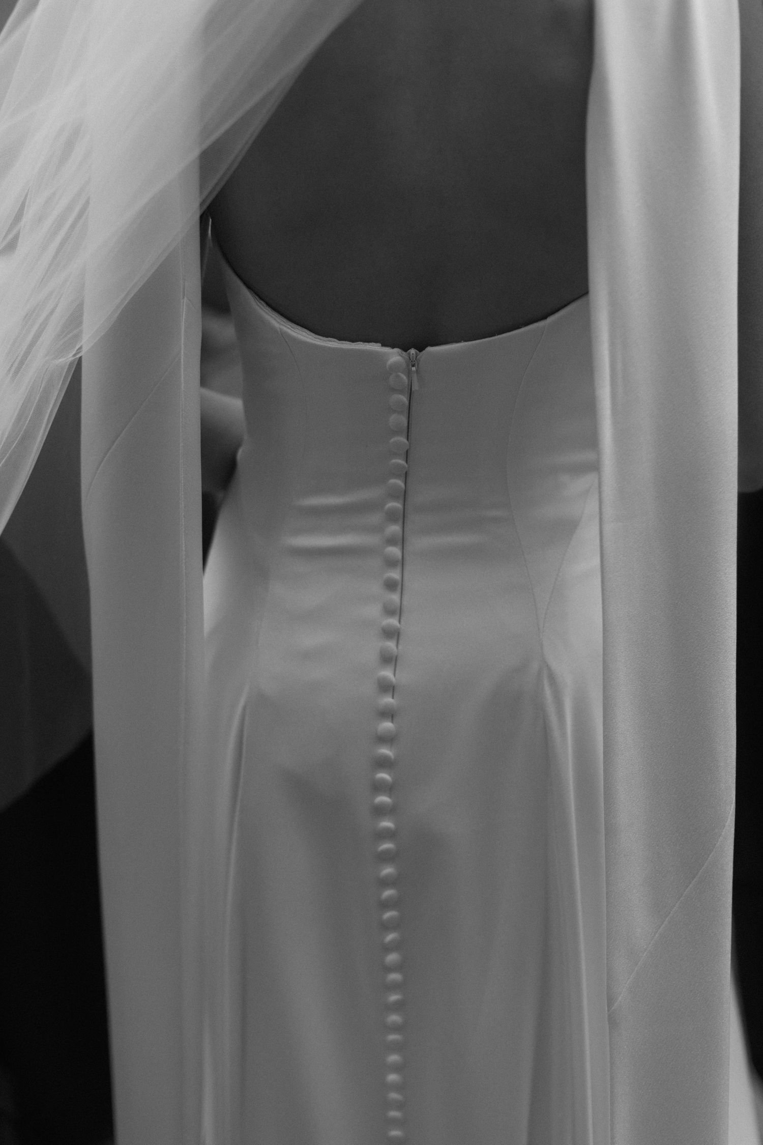 Close-up details of white wedding dress buttons and fabric.