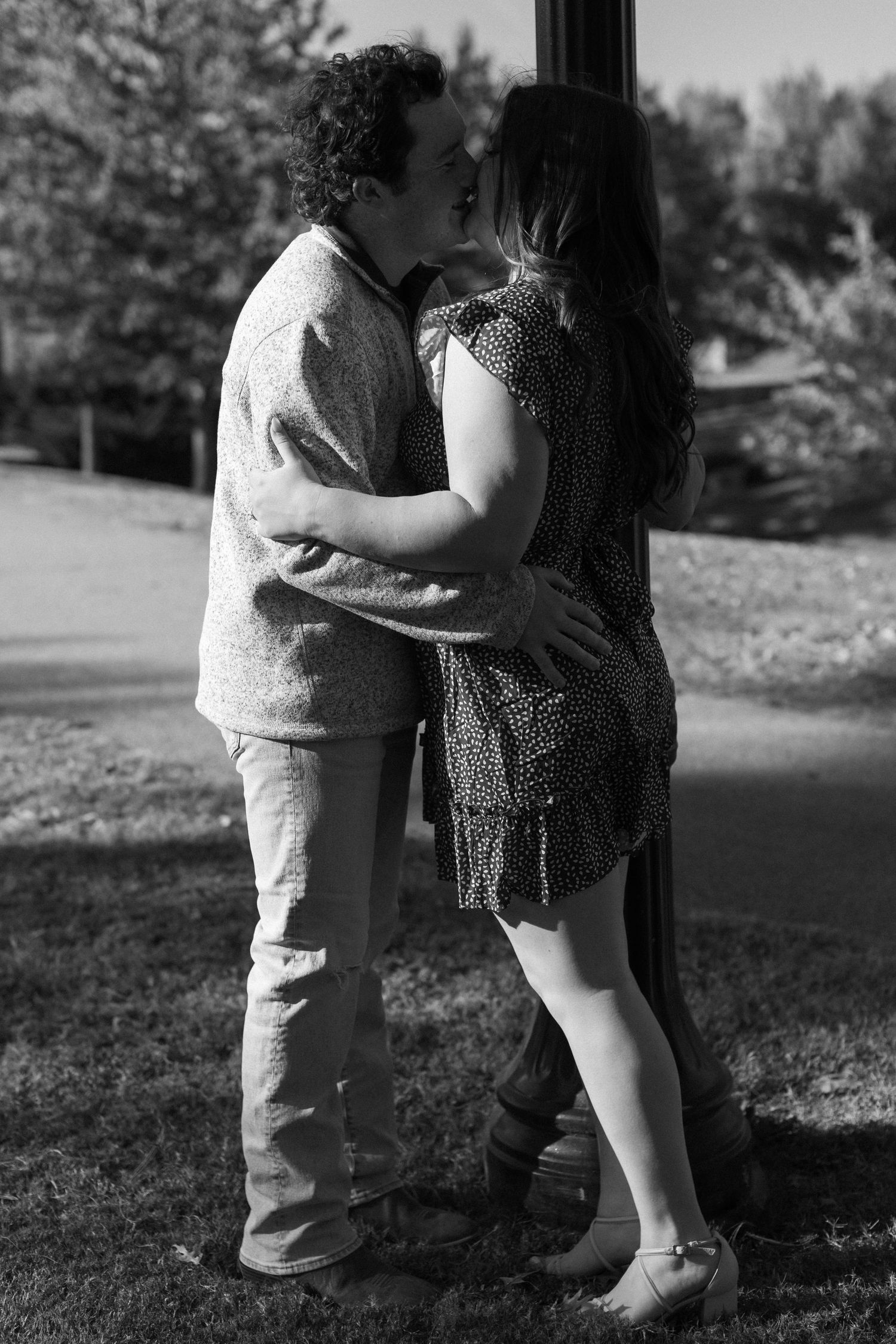 A black and white photo shows a couple sharing an intimate moment by a lamp post.