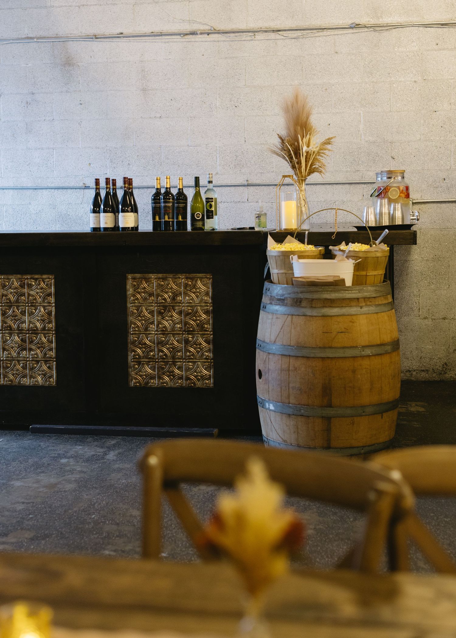 Rustic wine barrel bar setup with bottles displayed against a white wall.