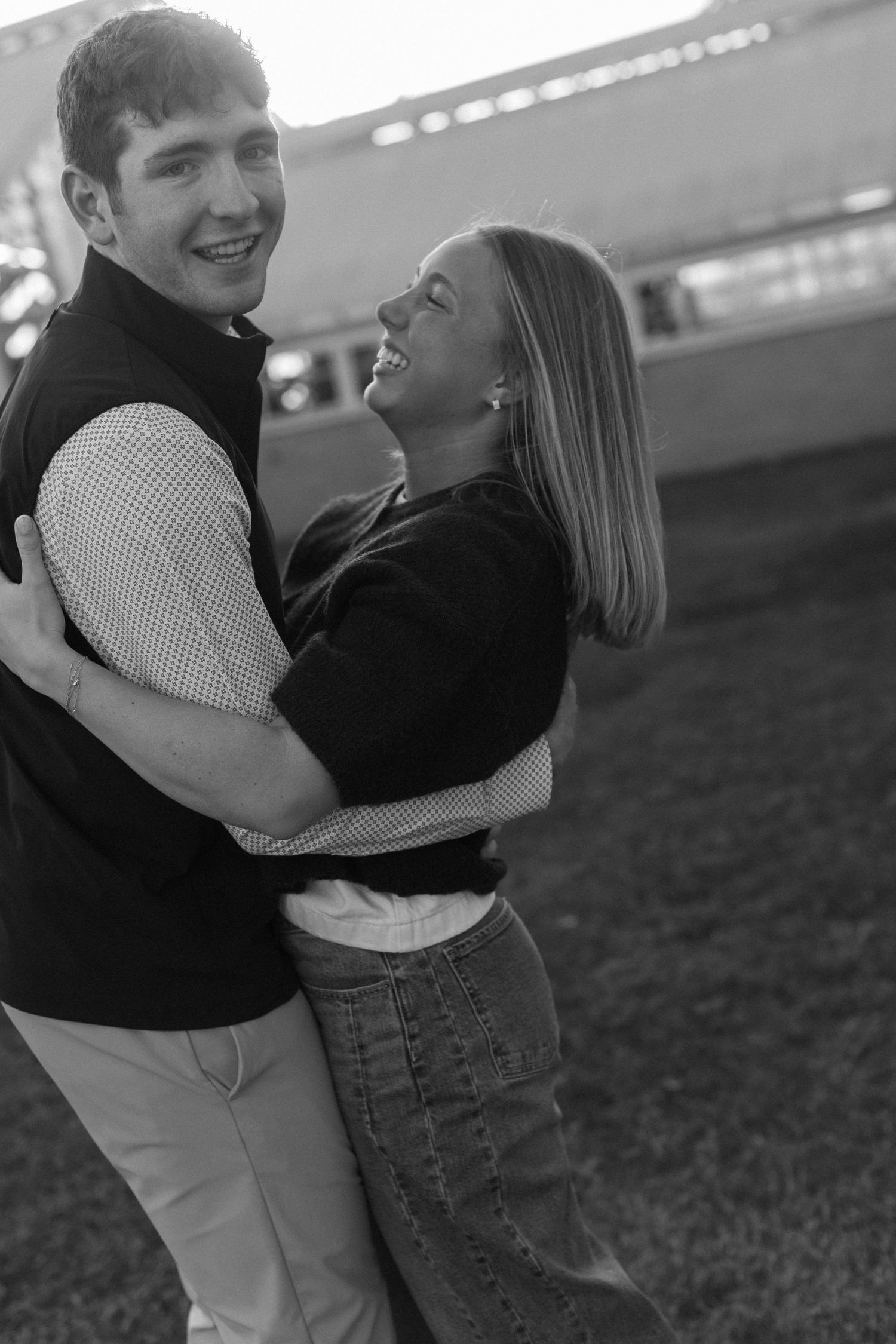 Romantic black and white portrait of a couple embracing and laughing together outdoors.