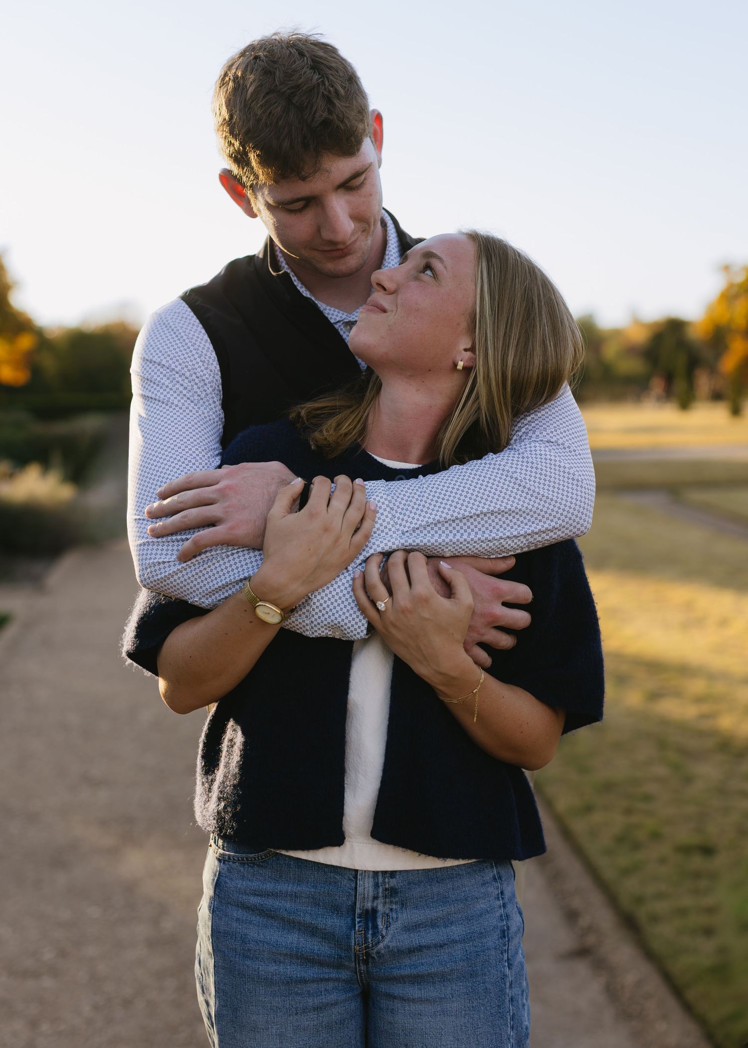 A romantic embrace captured in warm sunlight on a path outdoors.