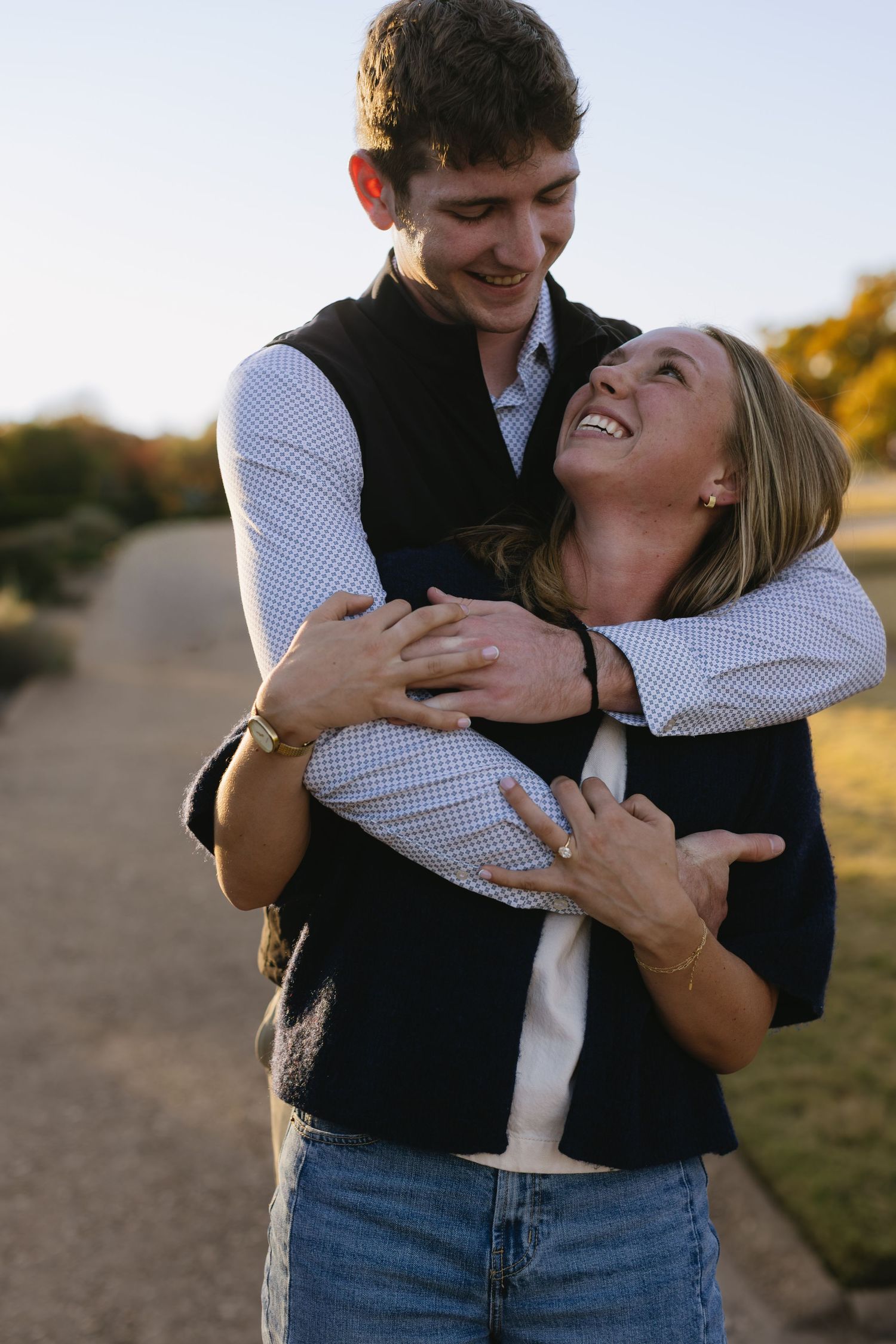 Playful couple sharing joyful moments and embracing during a golden hour photo session outdoors.