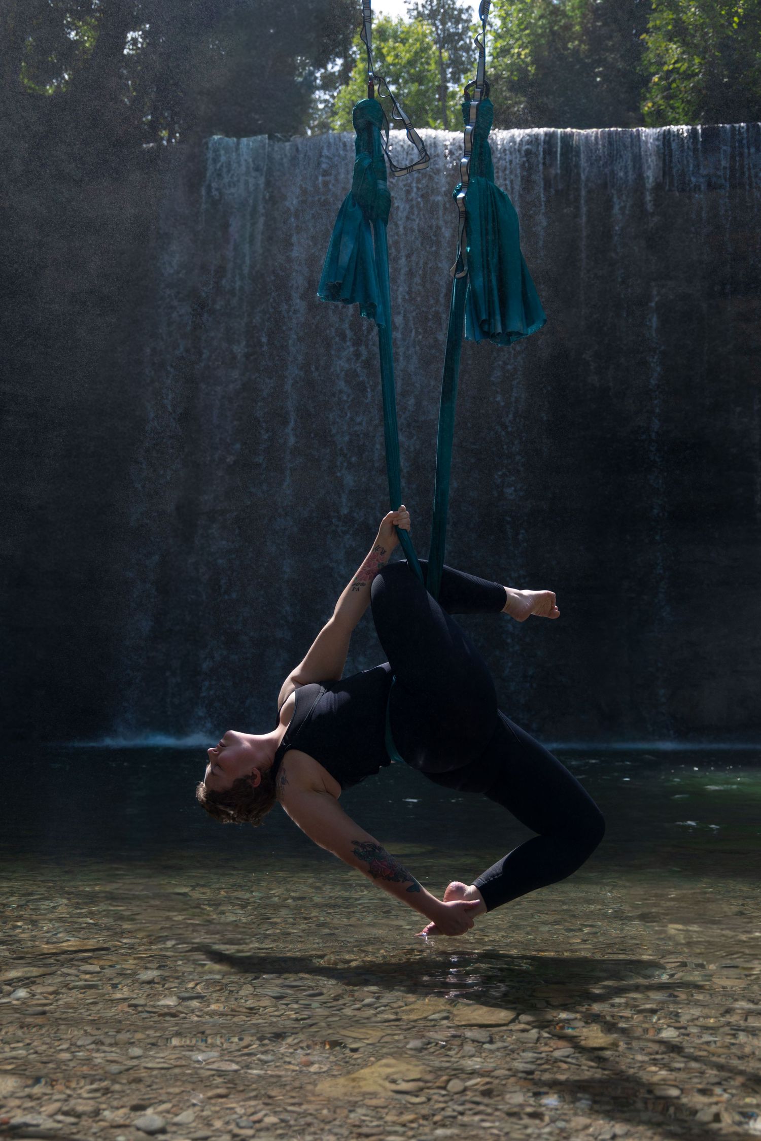 Creative portrait photography. Aerial yoga at Bridal Veil Falls in front of waterfall.