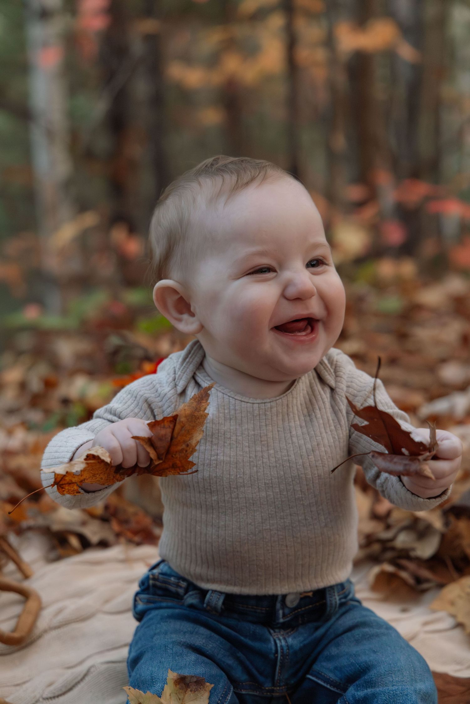 Toddler fall photoshoot. Baby holding leaves and smiling.