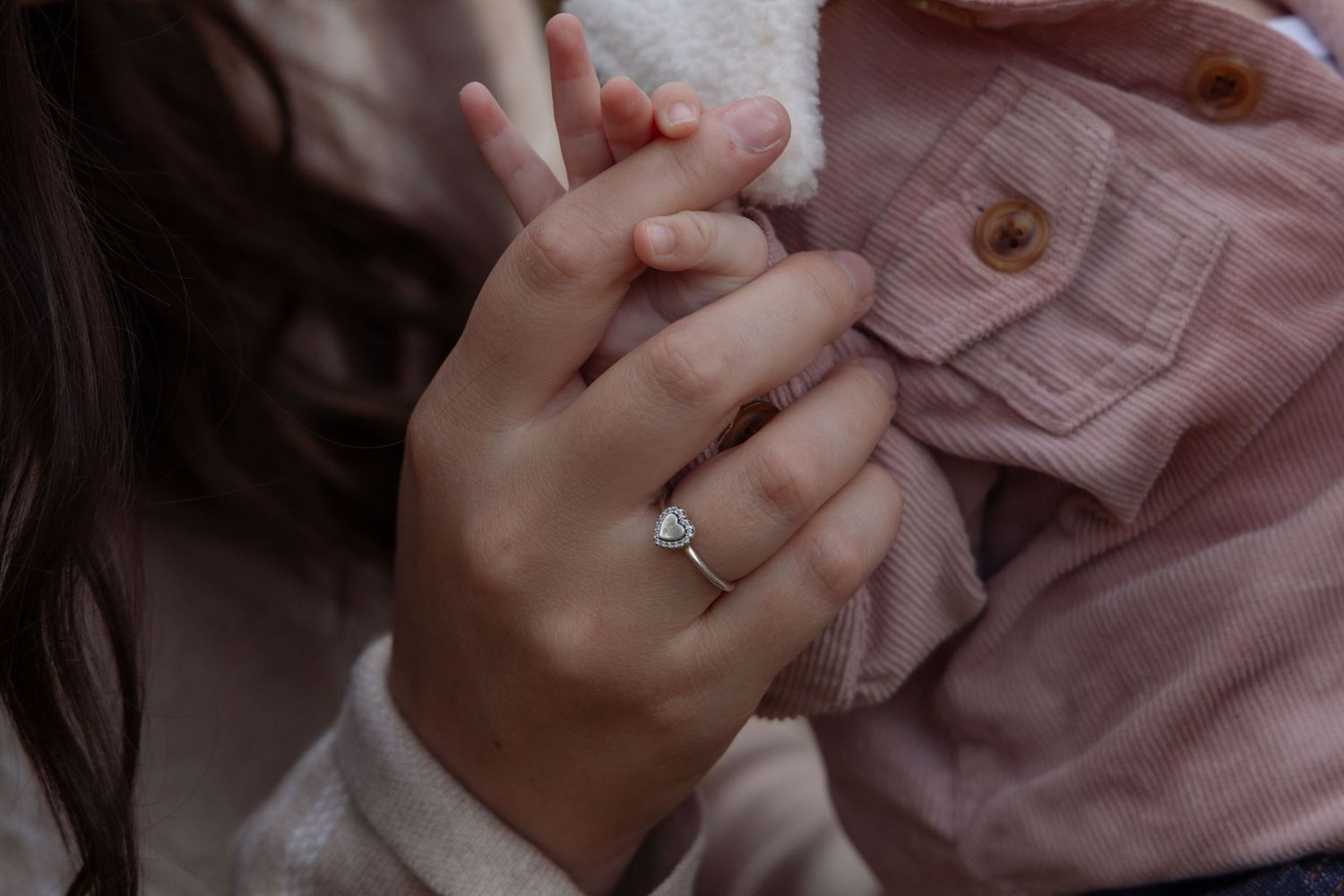 Close-up of mom and baby holding hands.