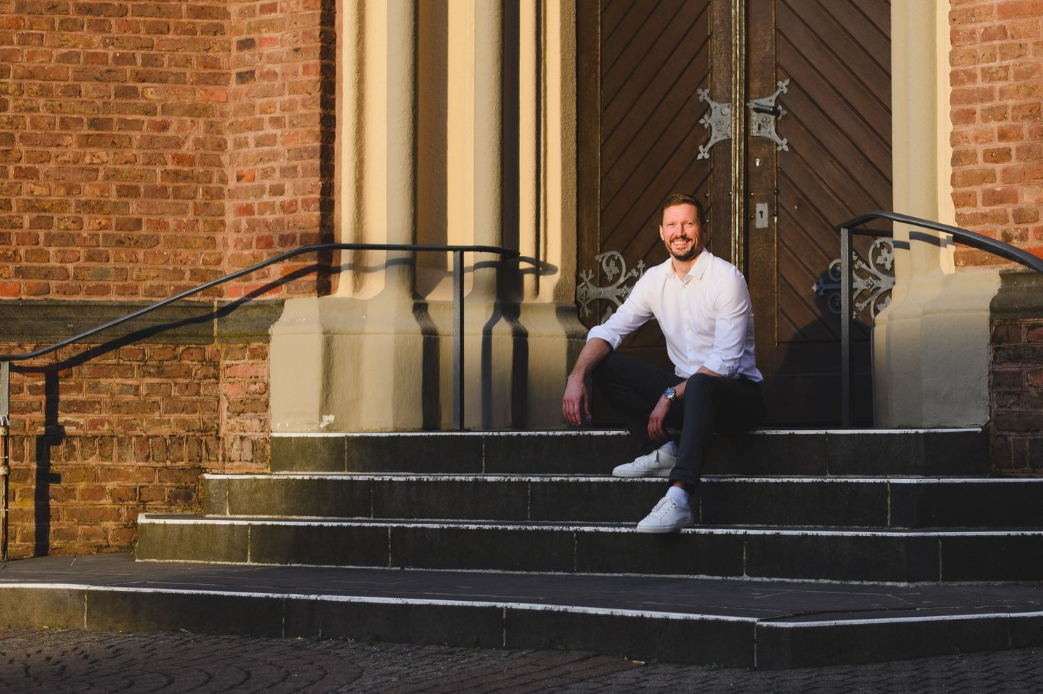 Fotograf sitzt auf der Treppe vor eine Kirchentür