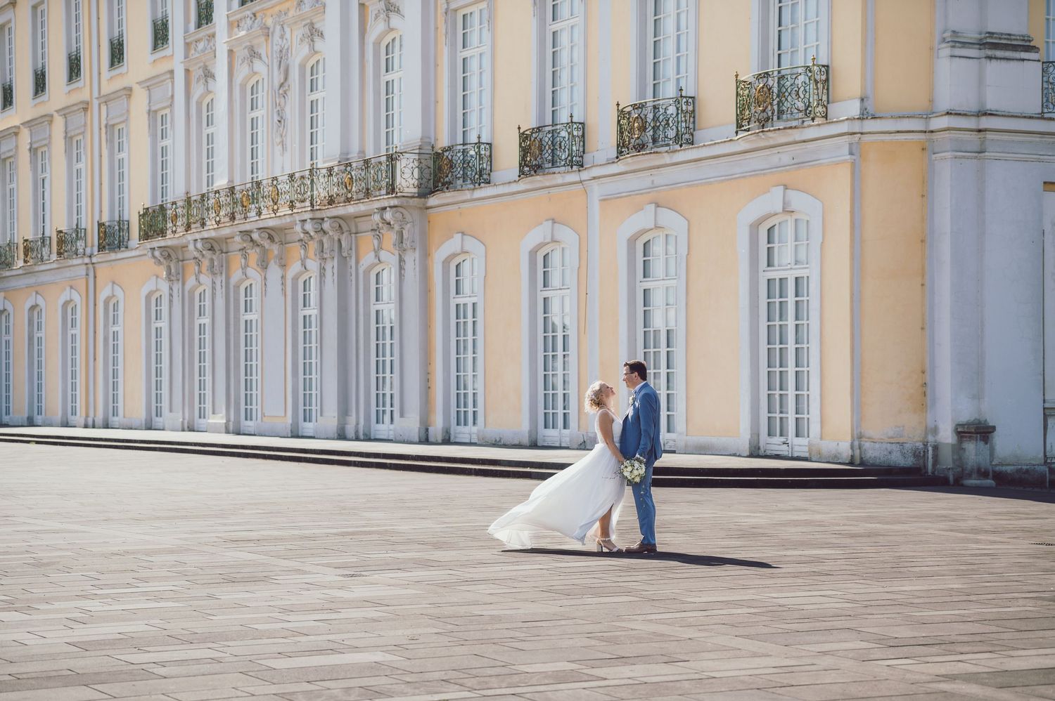 Hochzeitspaar posiert vor barockem Schloss