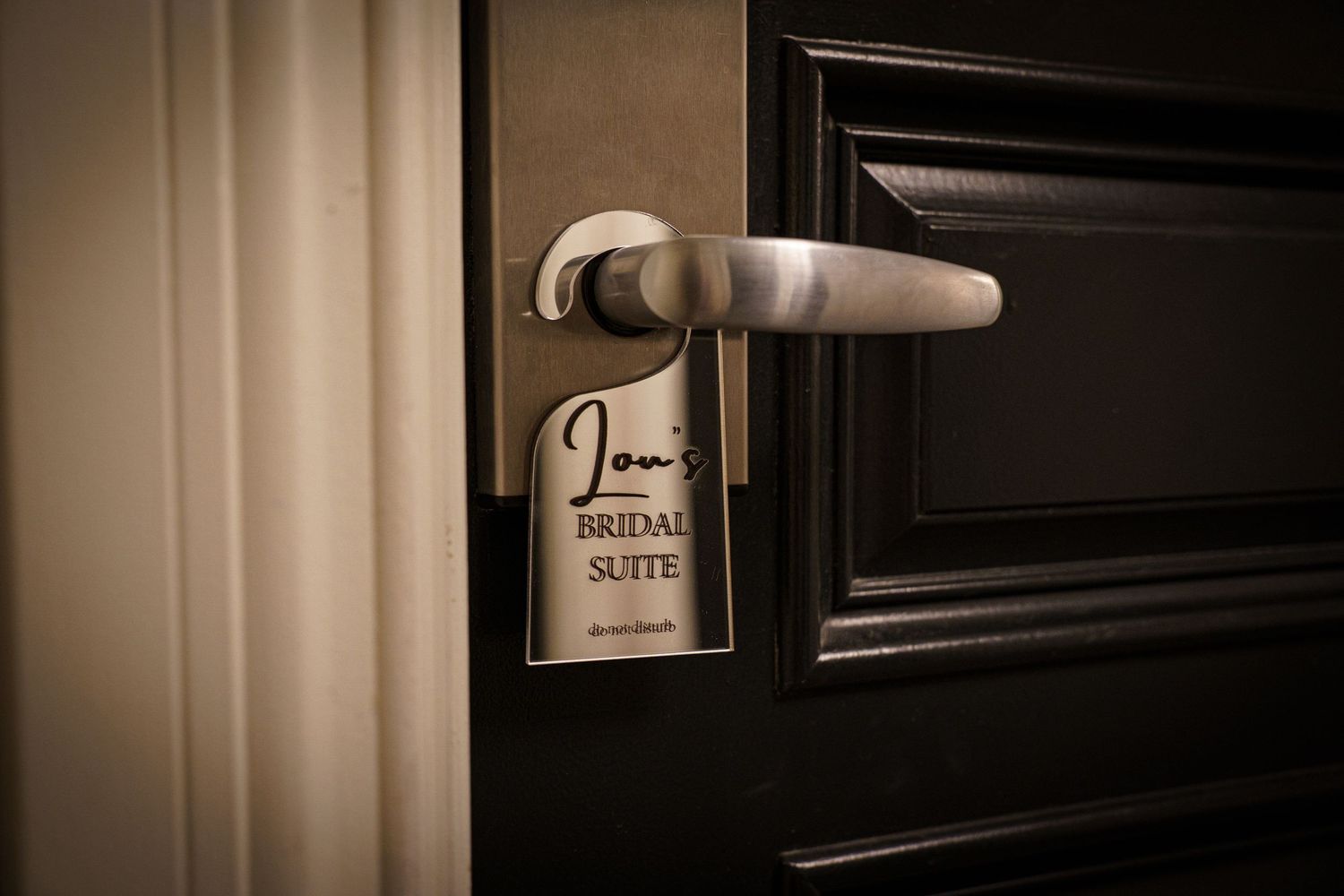 Personalized bridal suite door hanger sign hanging on a dark wooden hotel room door handle.