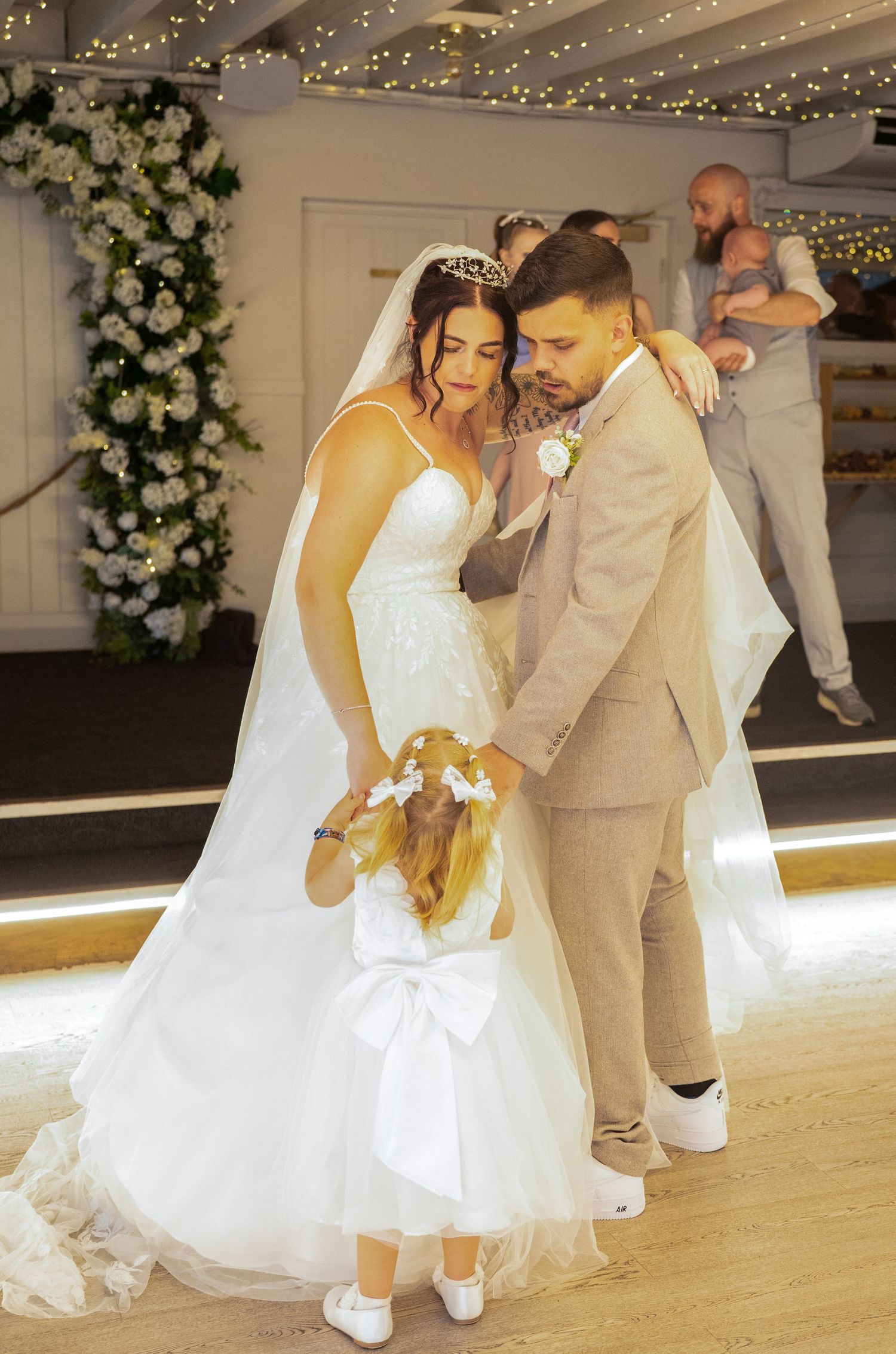 A bride and groom share their first dance with a flower girl joining them on the dance floor.