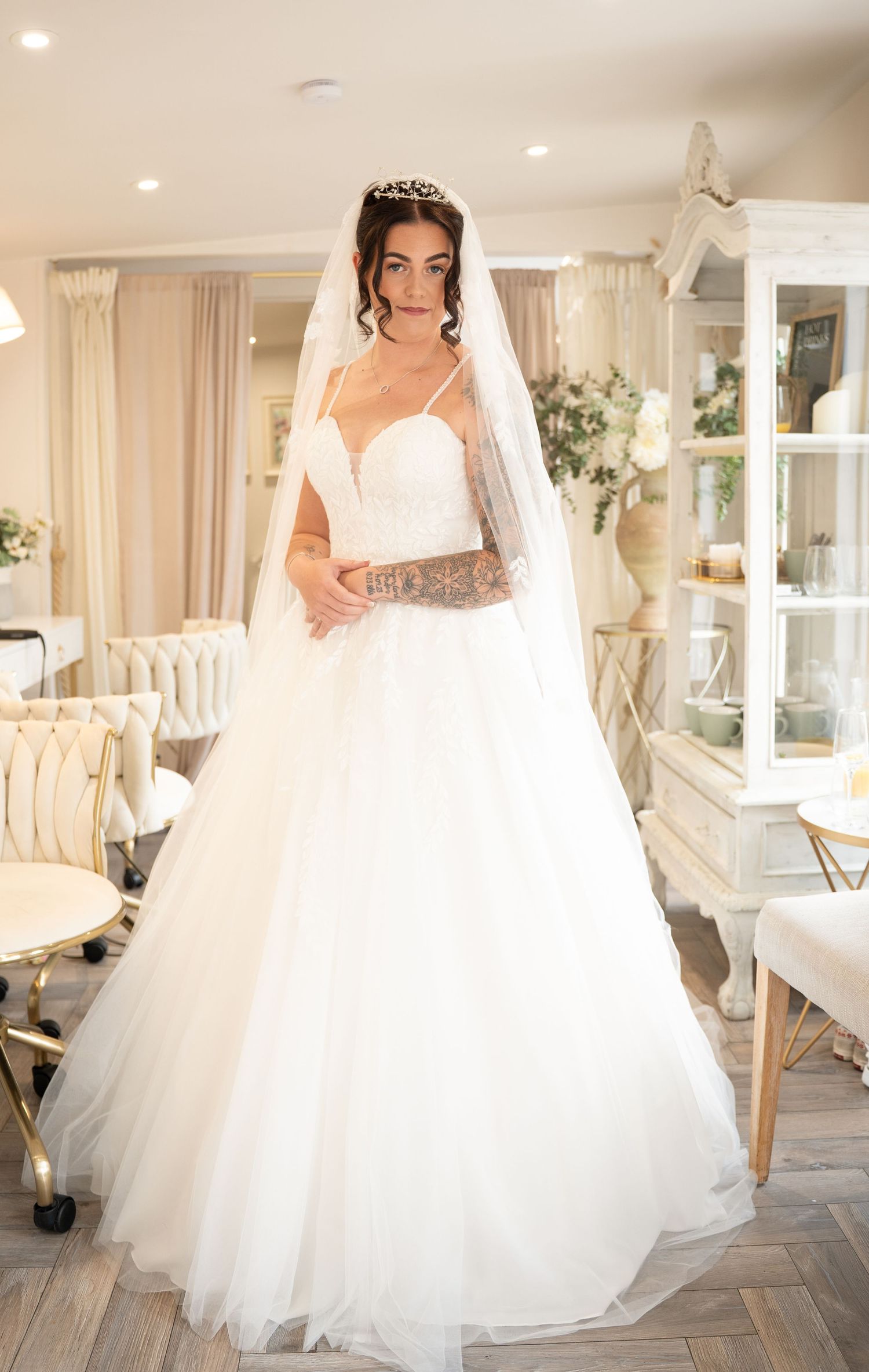 Bride in a white ballgown wedding dress with veil and tiara posing in a bridal boutique.