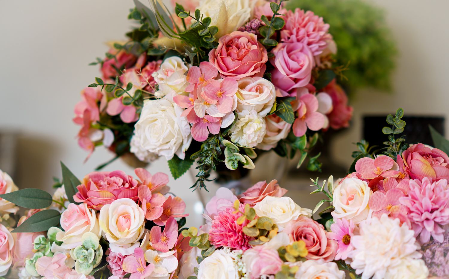 Elegant pink and white wedding flower arrangements with roses, dahlias, and lush greenery centerpieces.