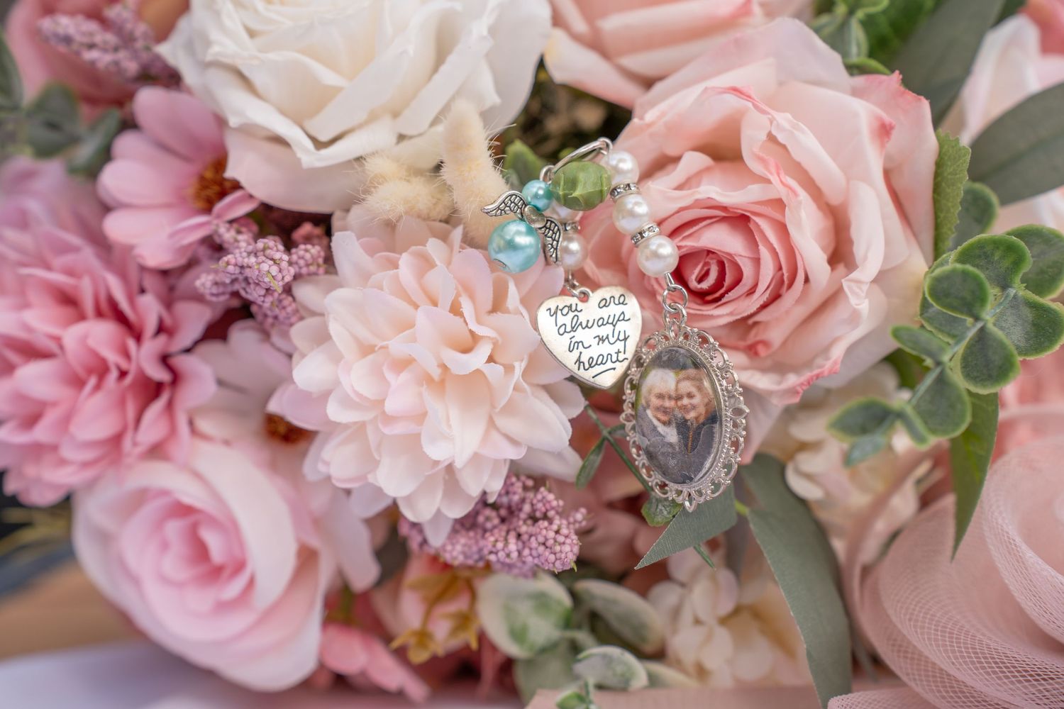 Pink wedding bouquet with roses and dahlias featuring memorial photo charm keepsake.