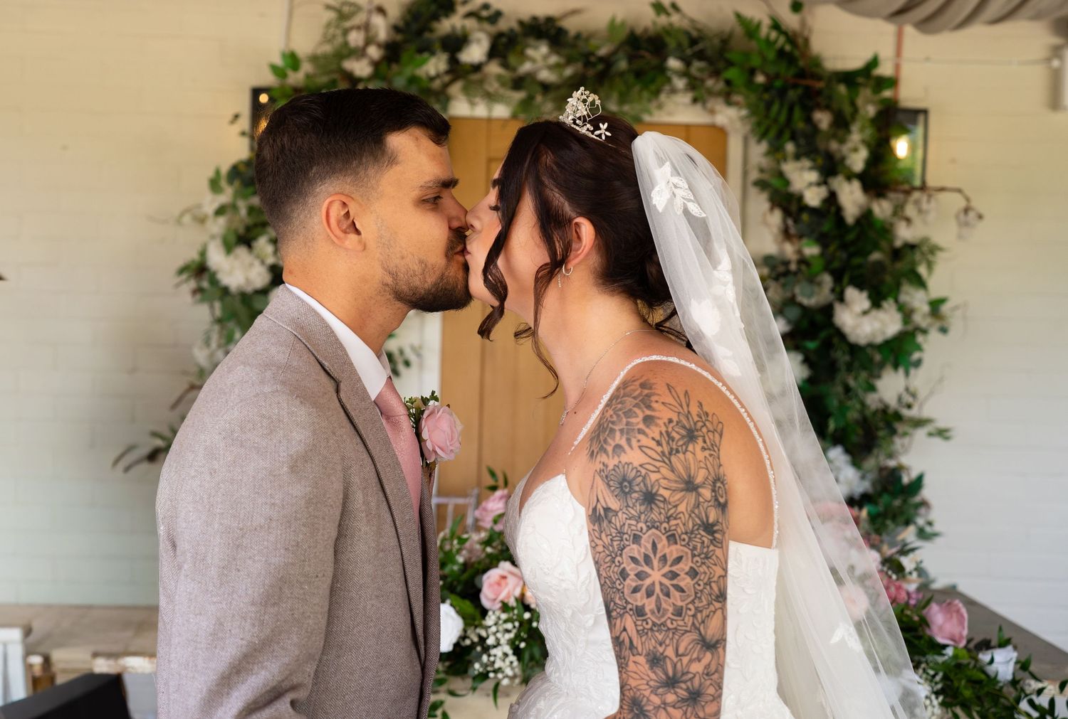 Bride and groom sharing intimate moment at floral wedding altar during ceremony.