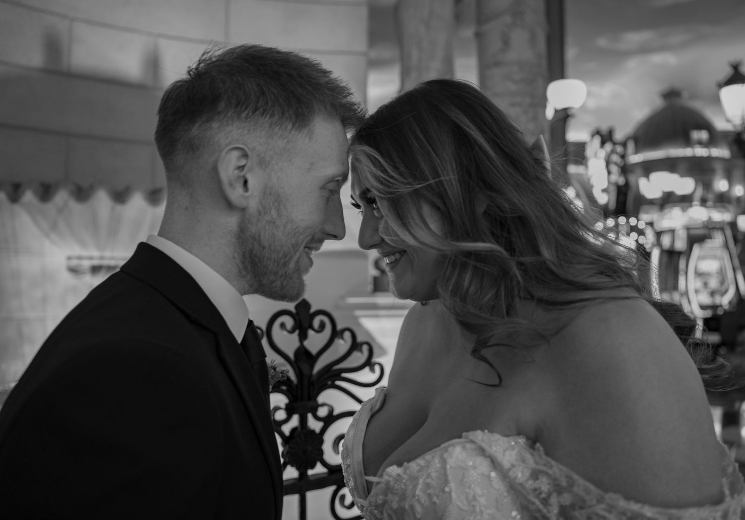 Black and white photo of bride and groom sharing an intimate moment, foreheads touching, smiling at each other.