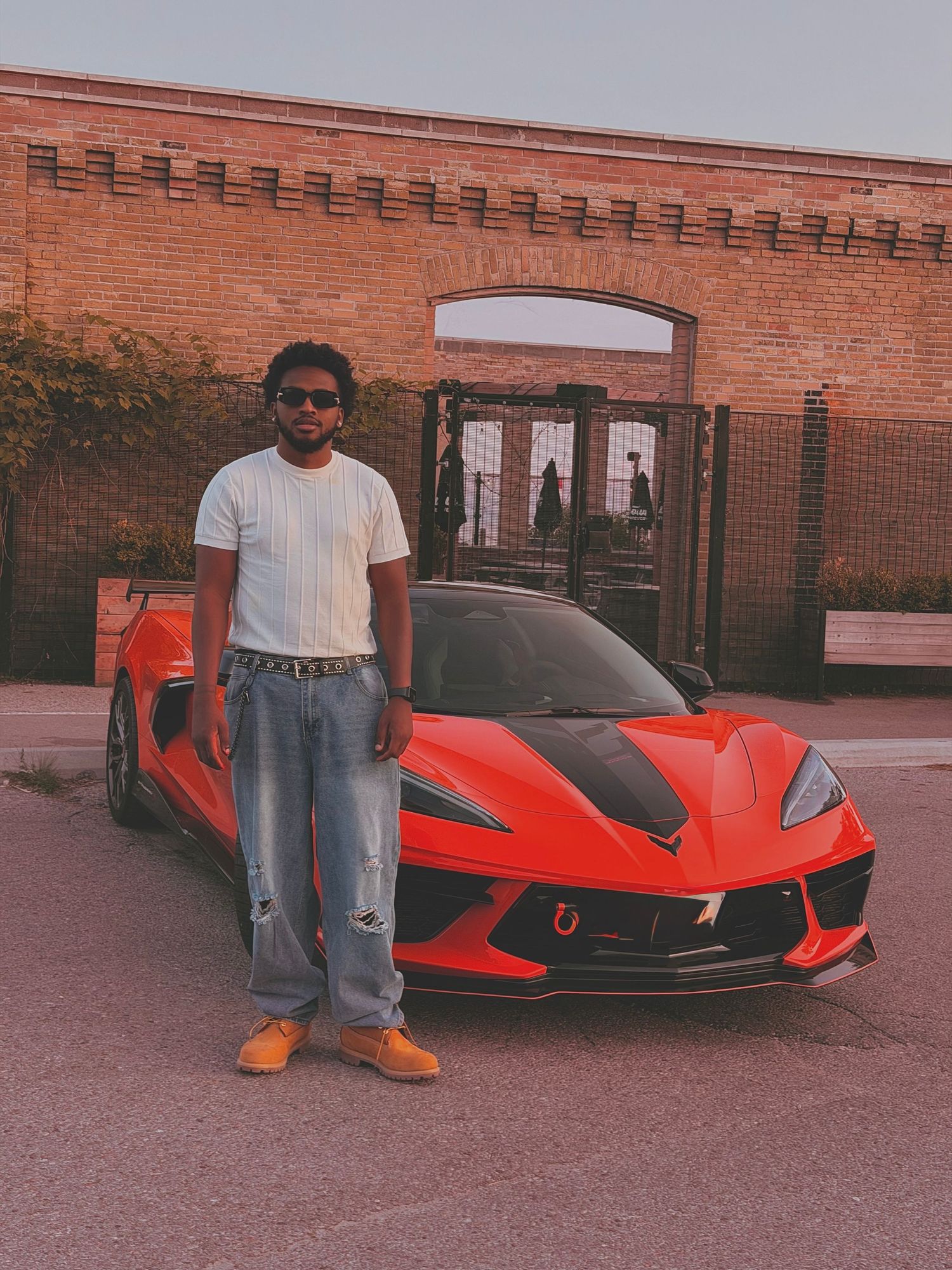 a guy standing in front of a luxury orange car
