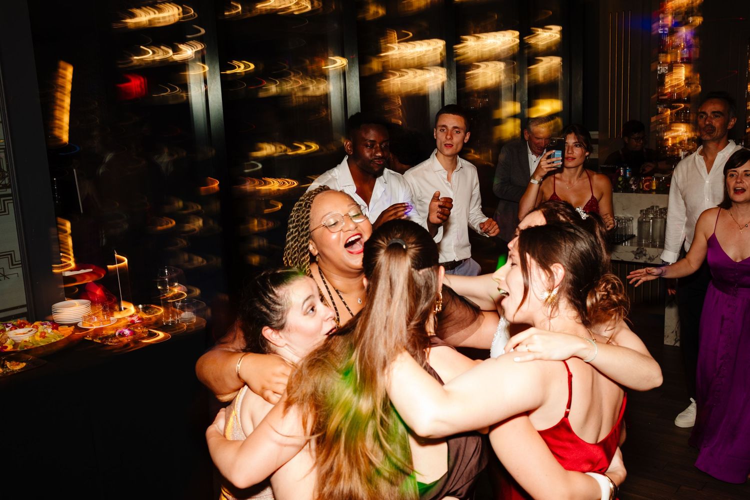 Wedding guests form a circle while dancing and singing at a lively reception.
