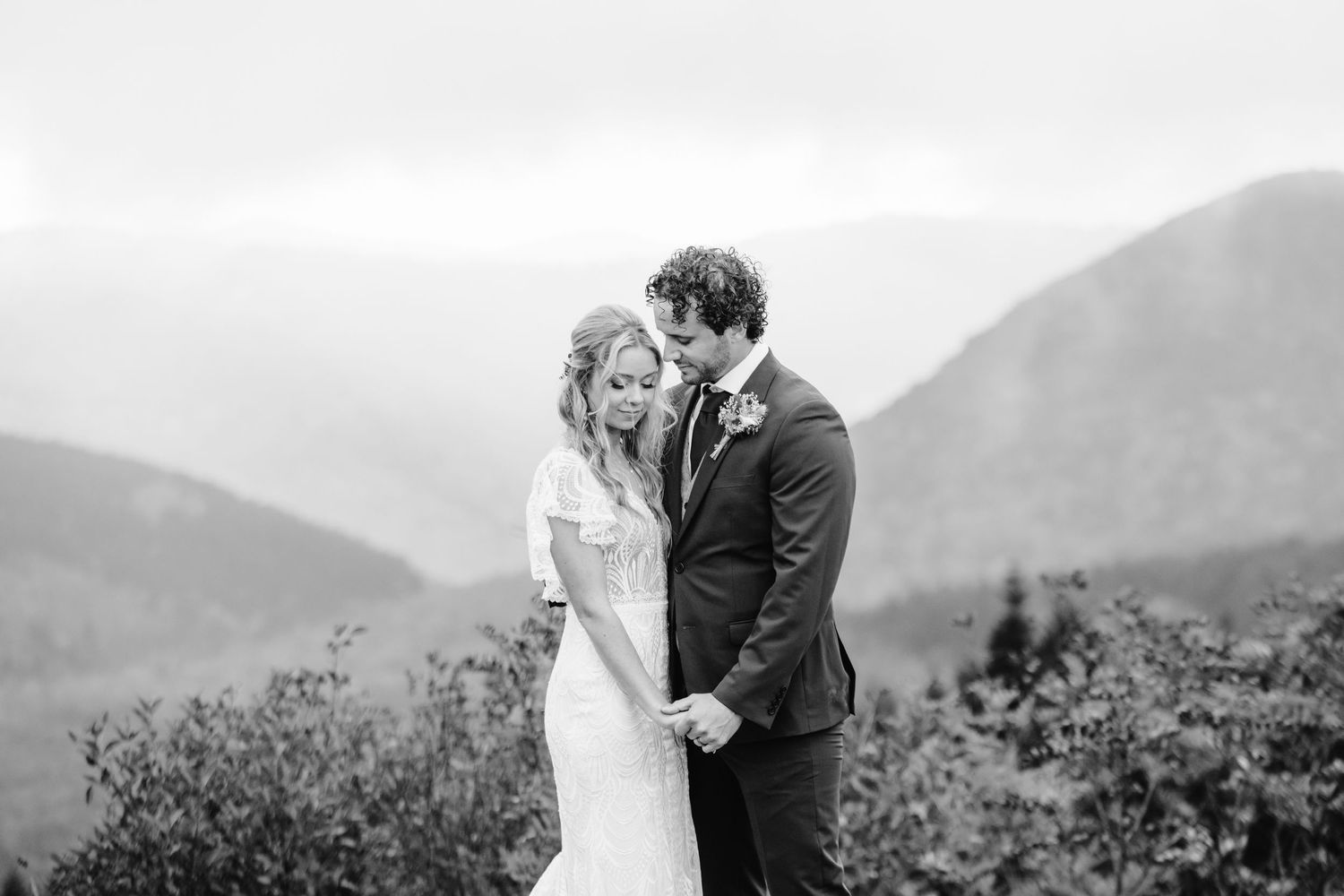 Black and white intimate wedding portrait with mountain vista in background.