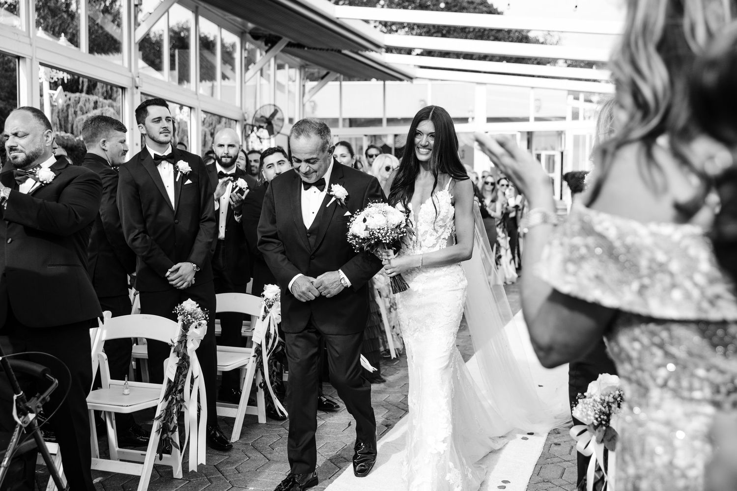 Wedding ceremony processional on a stone pathway with guests watching.