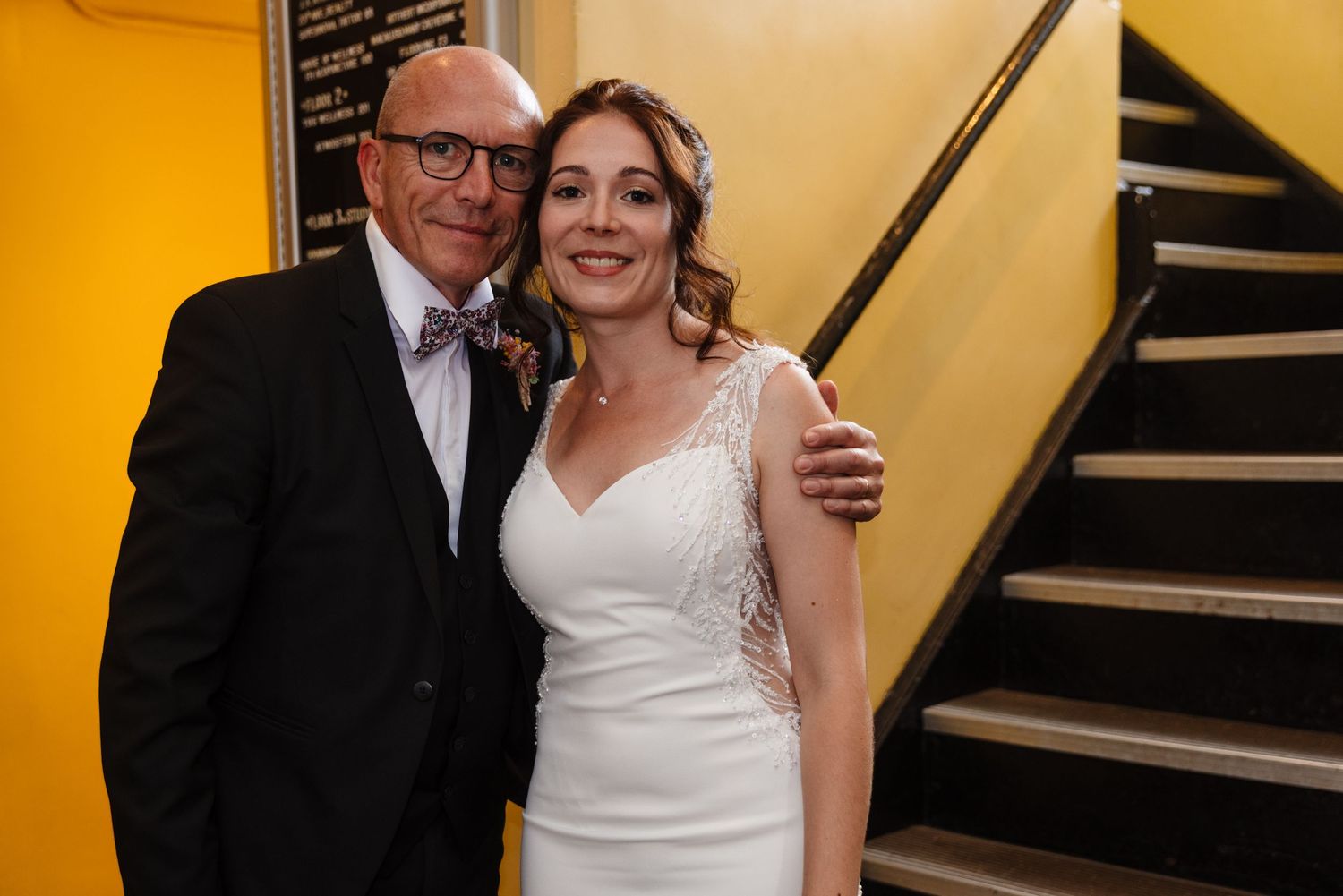 A warm moment captured near a staircase at a wedding celebration.