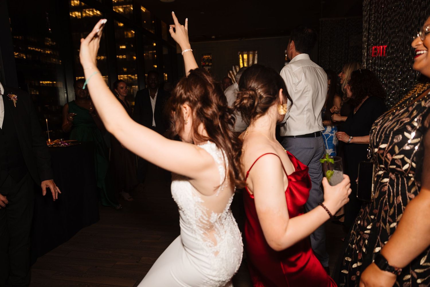 Wedding party dancing enthusiastically at a dimly lit reception venue.