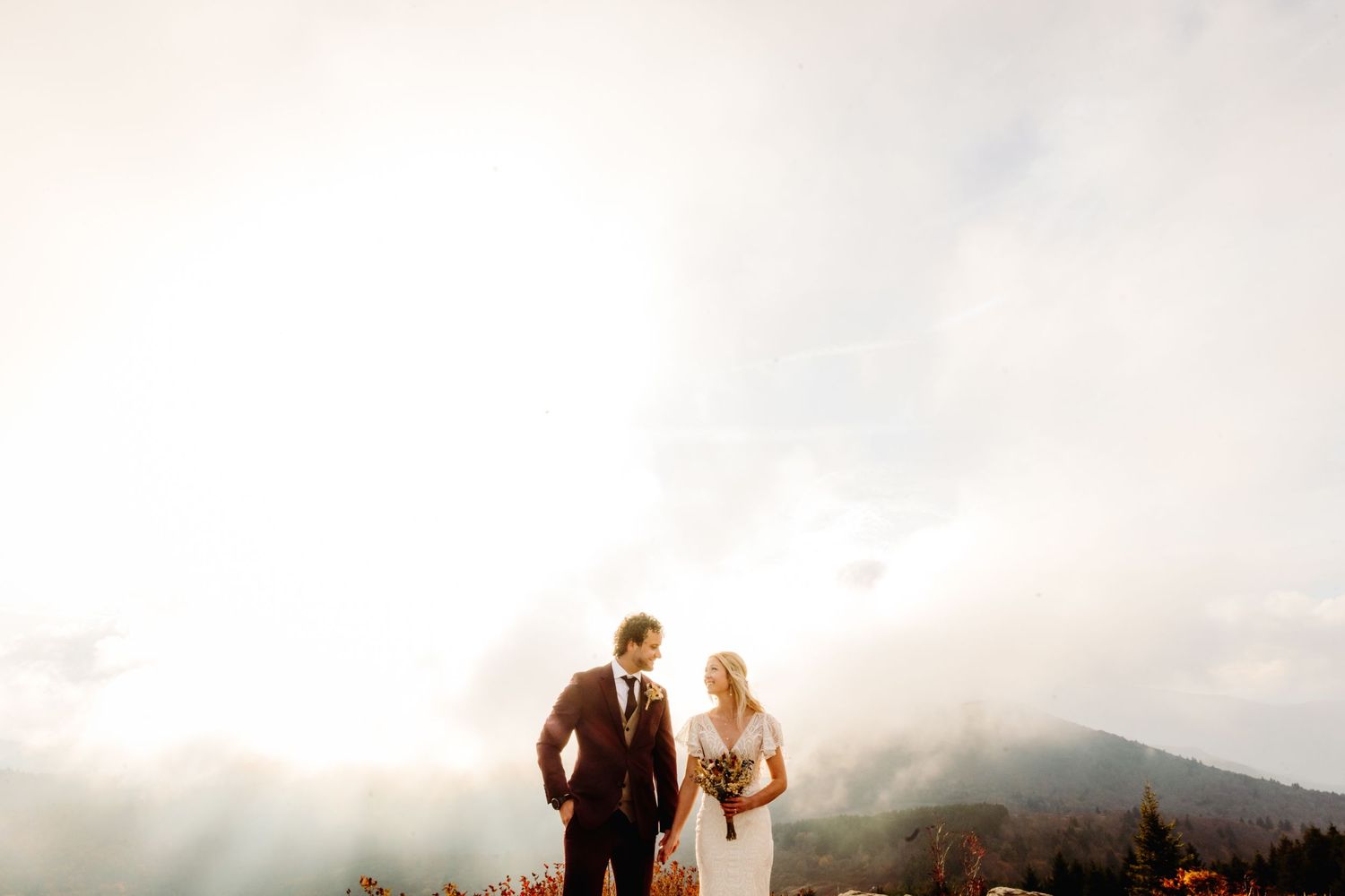 Dreamy mountaintop wedding portrait with misty valley backdrop.