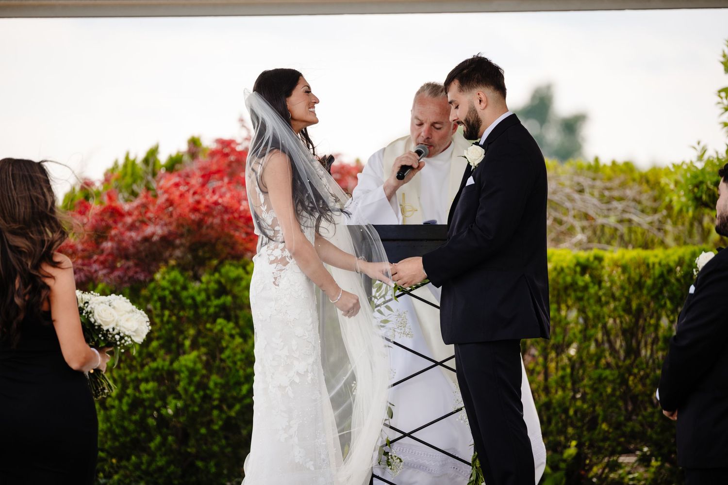 Wedding couple shares intimate moments in a lush garden with vibrant red Japanese maple trees in the background.
