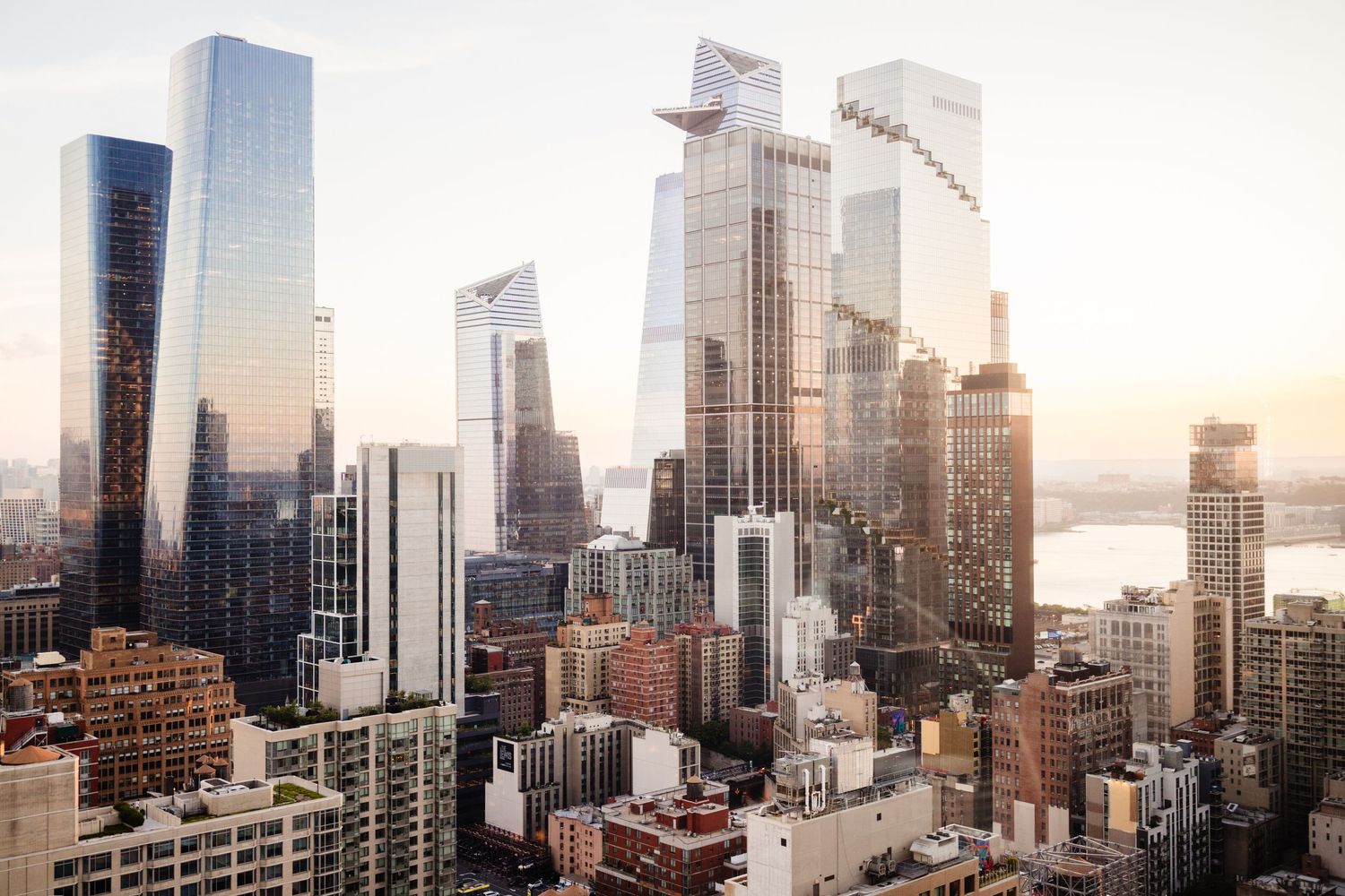 Modern skyscrapers and luxury high-rise buildings tower over New York City during sunset.