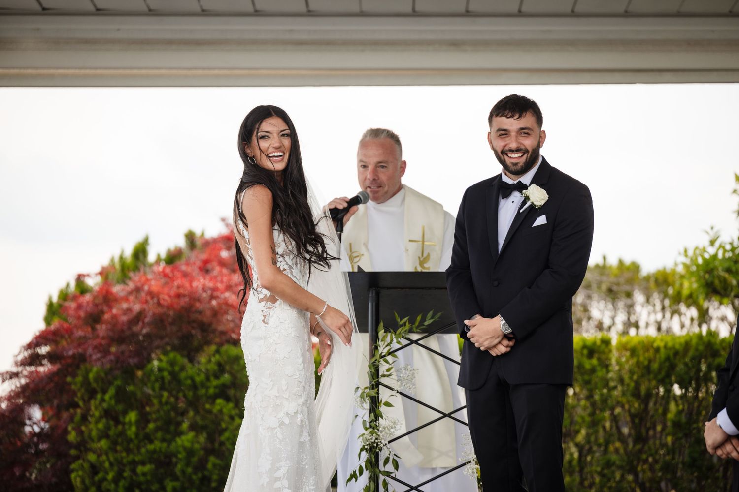 Garden wedding ceremony with elegant white architectural elements and red foliage.