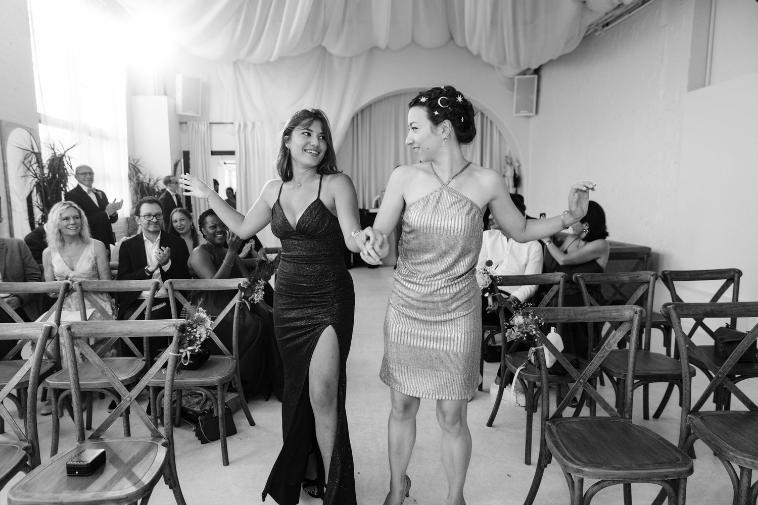 Wedding guests react with joy and excitement during an emotional moment at a beautifully decorated indoor reception.