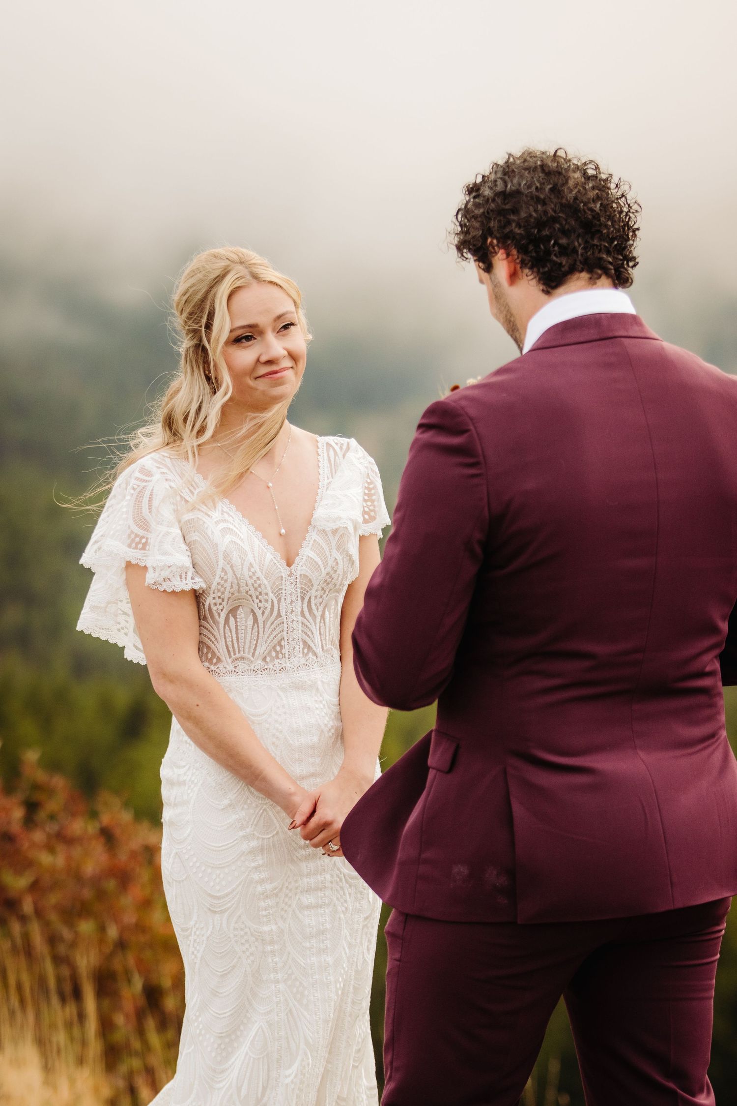 A couple exchanges vows during an outdoor autumn wedding ceremony with mountain views.