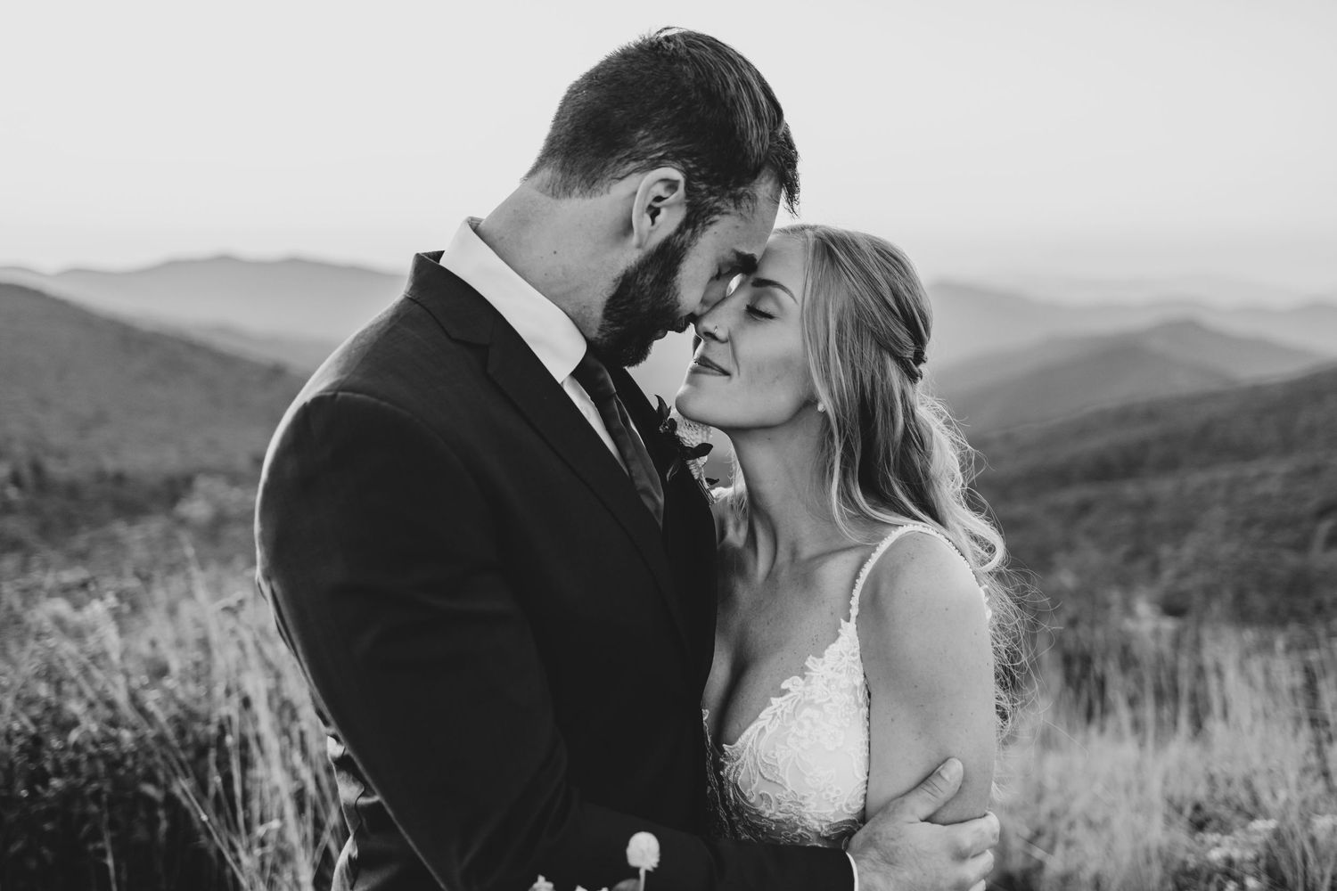 Black and white intimate wedding portrait with mountain scenery in background.