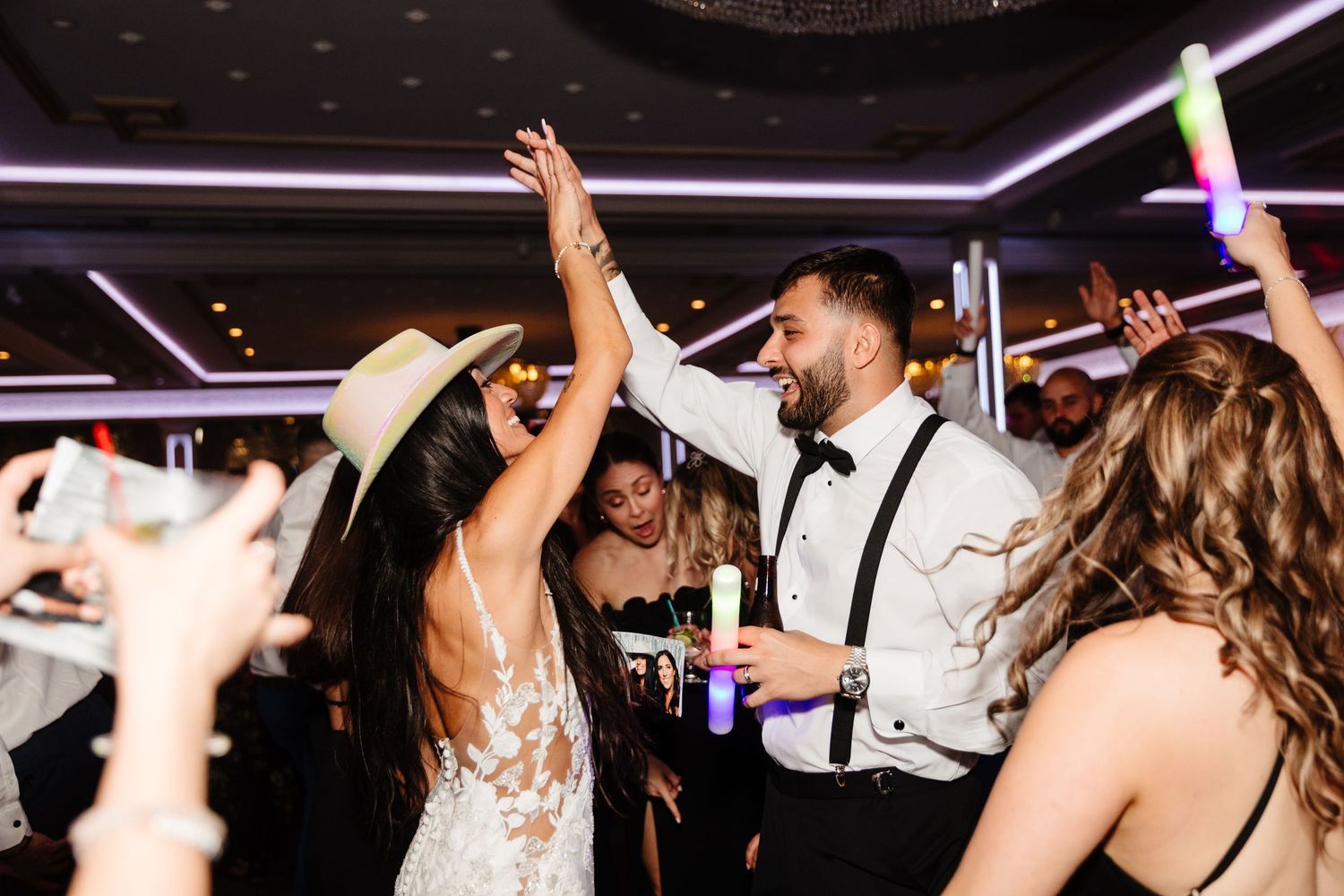 Crowded dance floor with guests dancing enthusiastically under modern lighting effects.