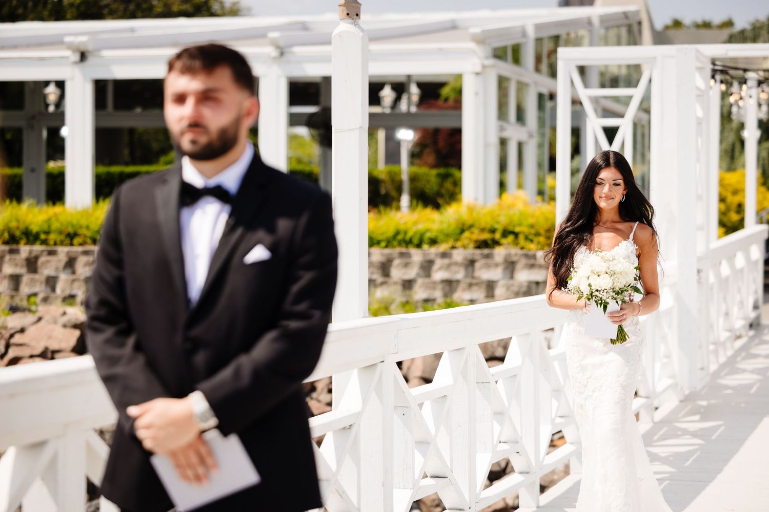 Elegant white wedding ceremony setup on a waterfront deck with classic architectural details.