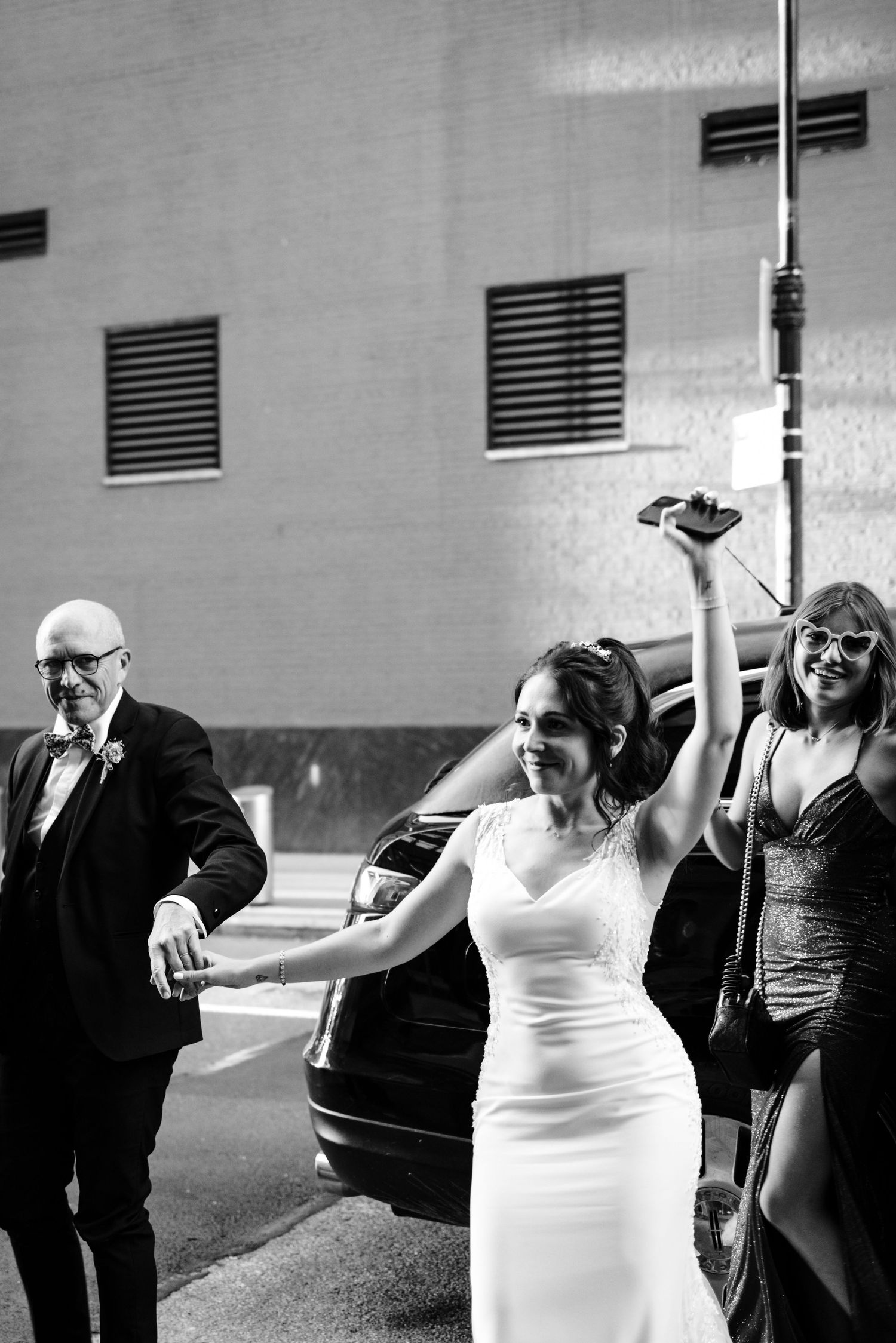 A celebratory moment outside with a bride and wedding party in black and white.