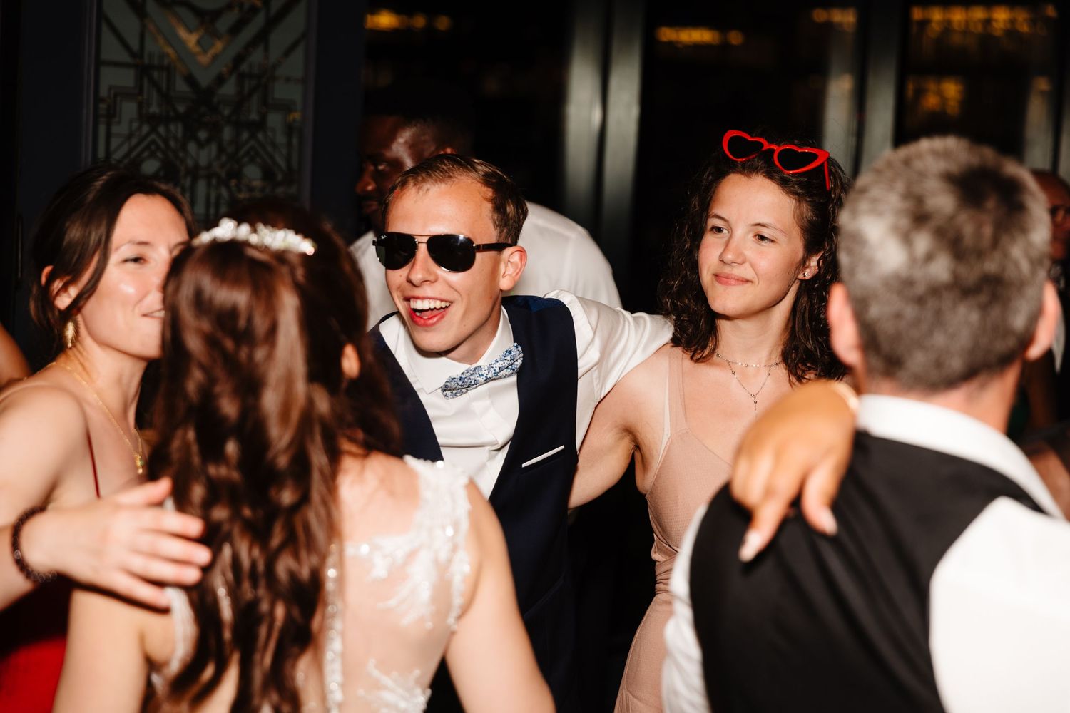 Wedding party dancing and celebrating with the bride and groom at a lively reception.