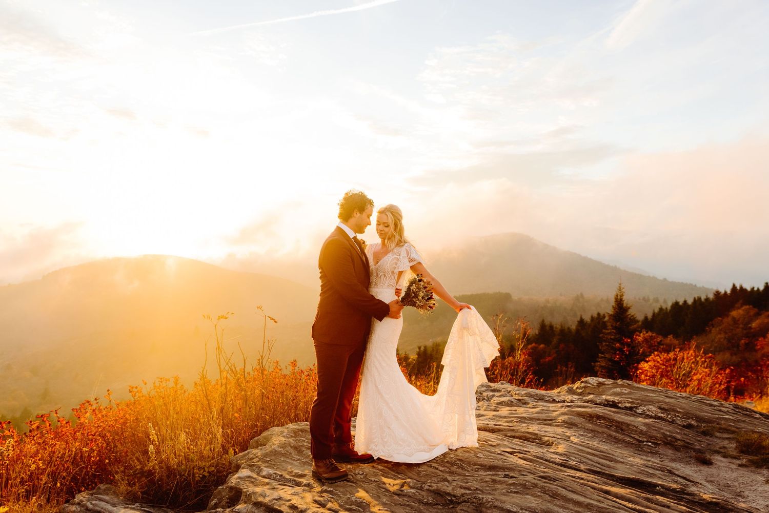Elegant wedding photography captures a sunset moment on a mountain peak.