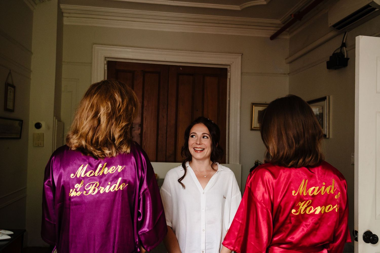 Wedding party members wearing colorful satin robes with embroidered text.