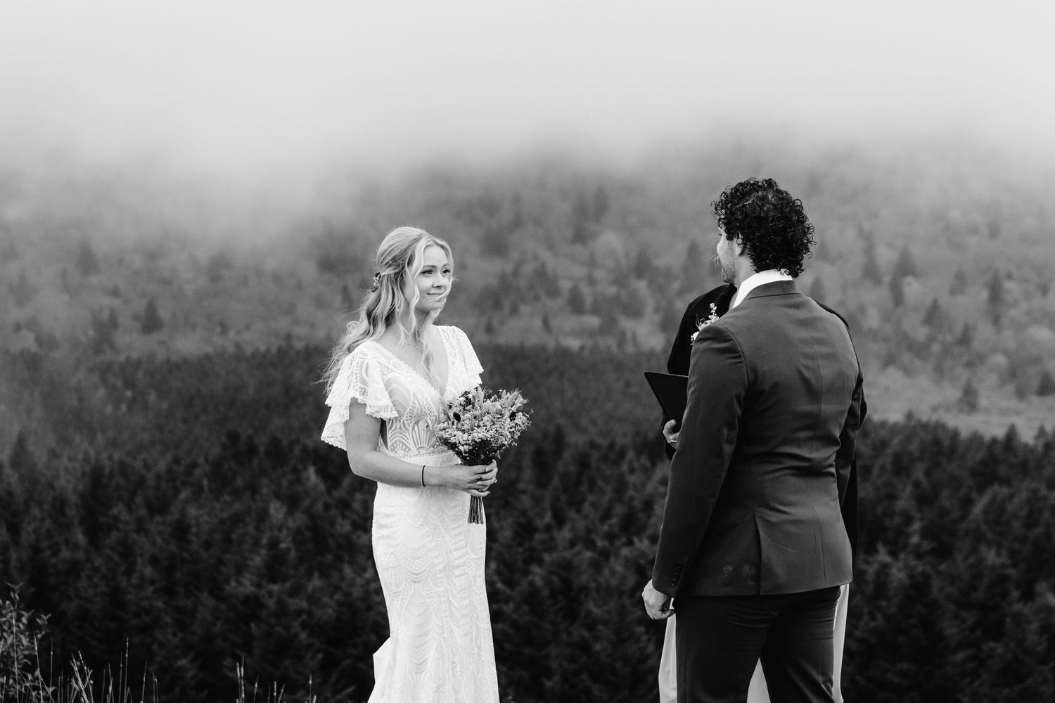 Black and white mountain wedding ceremony in foggy landscape.