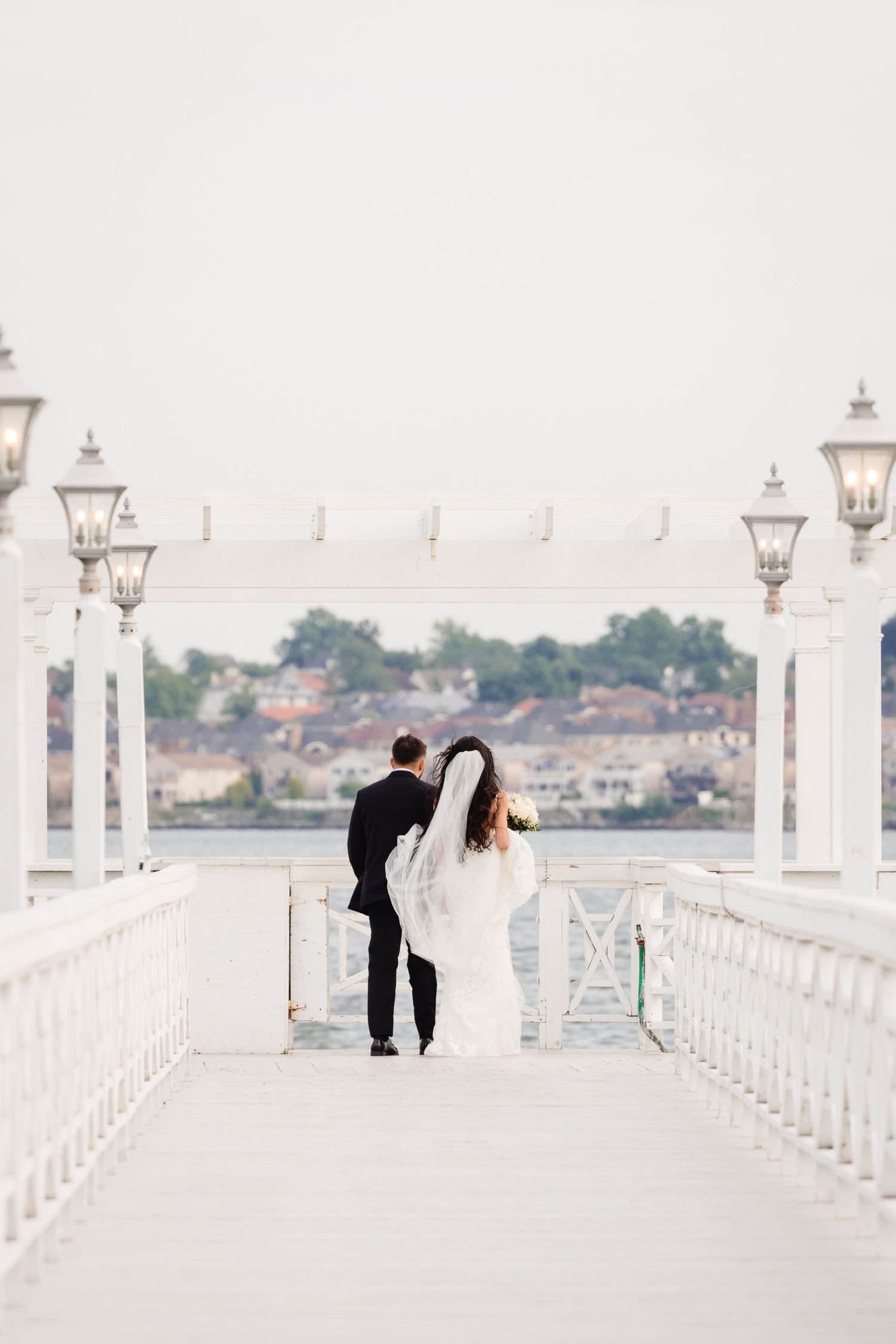Couple walking along a pristine white pier with ornate Victorian lampposts.