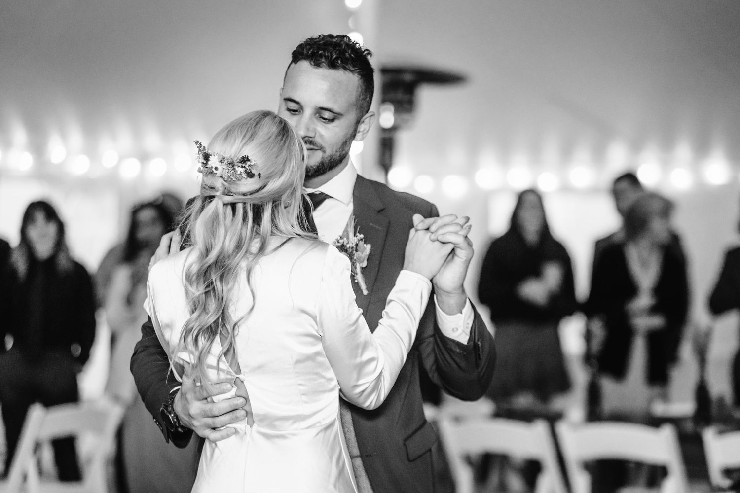 Couple shares romantic dance moment under tent lighting at reception.