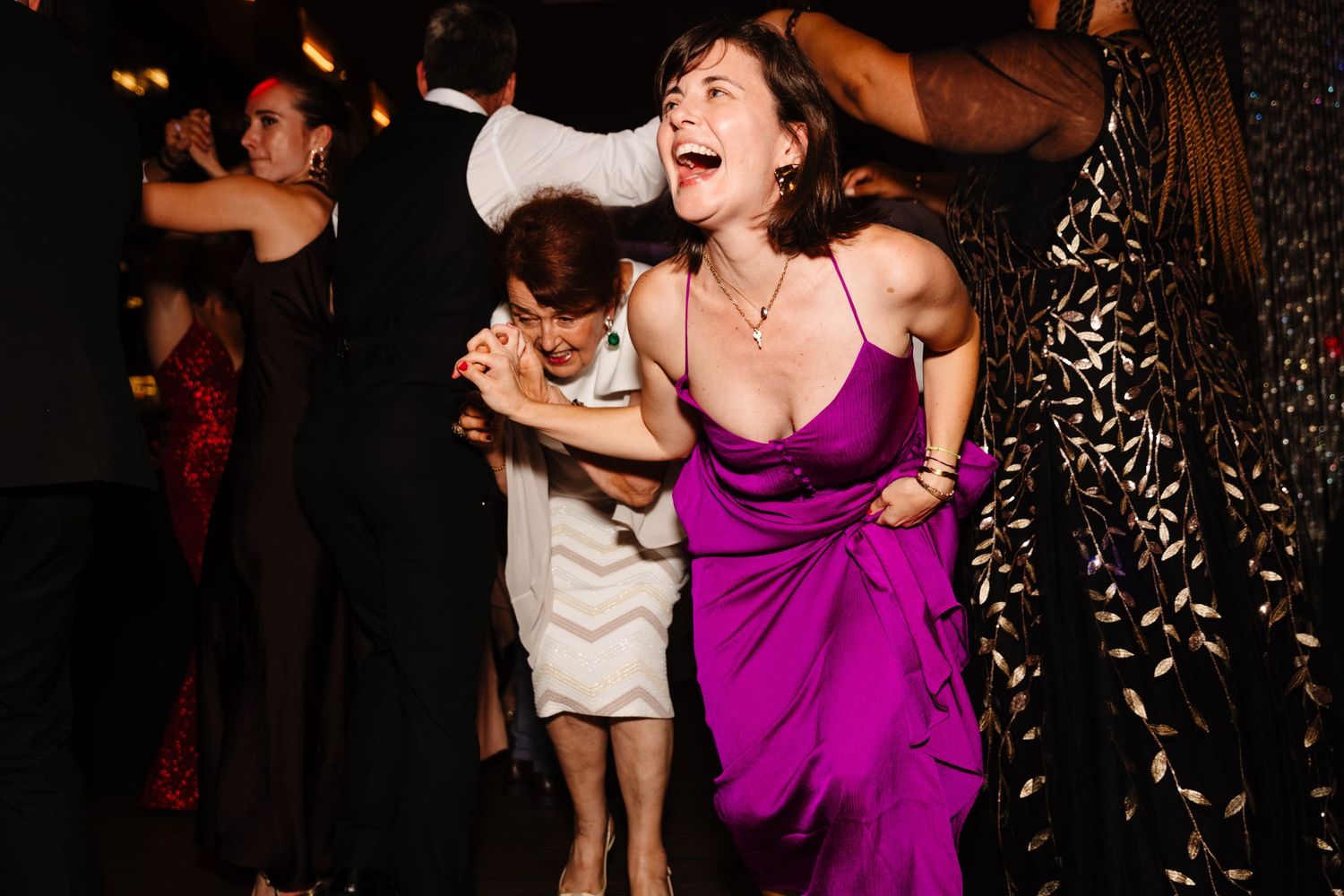 Woman in purple dress enjoying herself on a lively wedding reception dance floor.