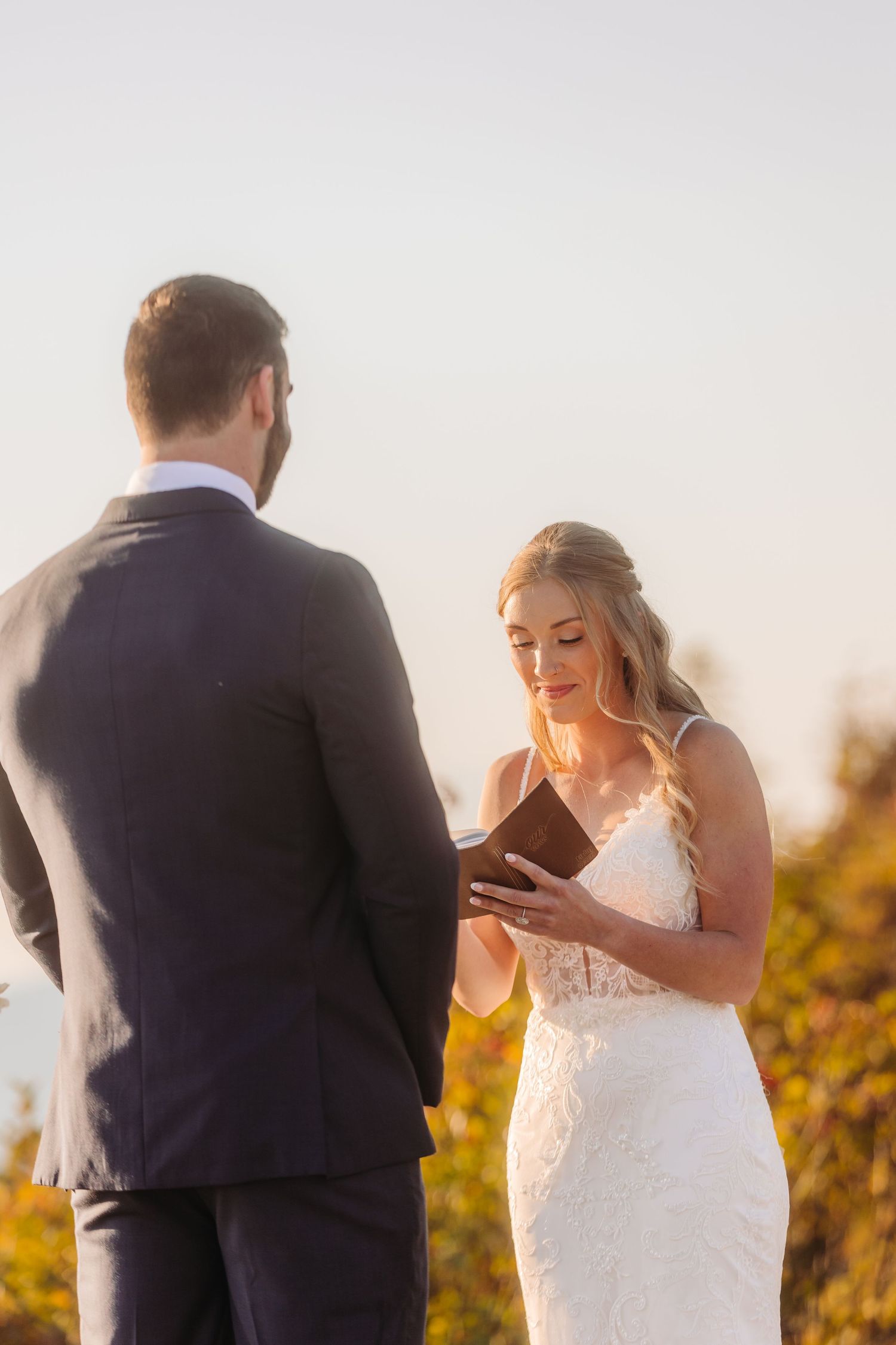 Wedding ceremony moment during golden hour as couple exchanges vows on mountaintop.