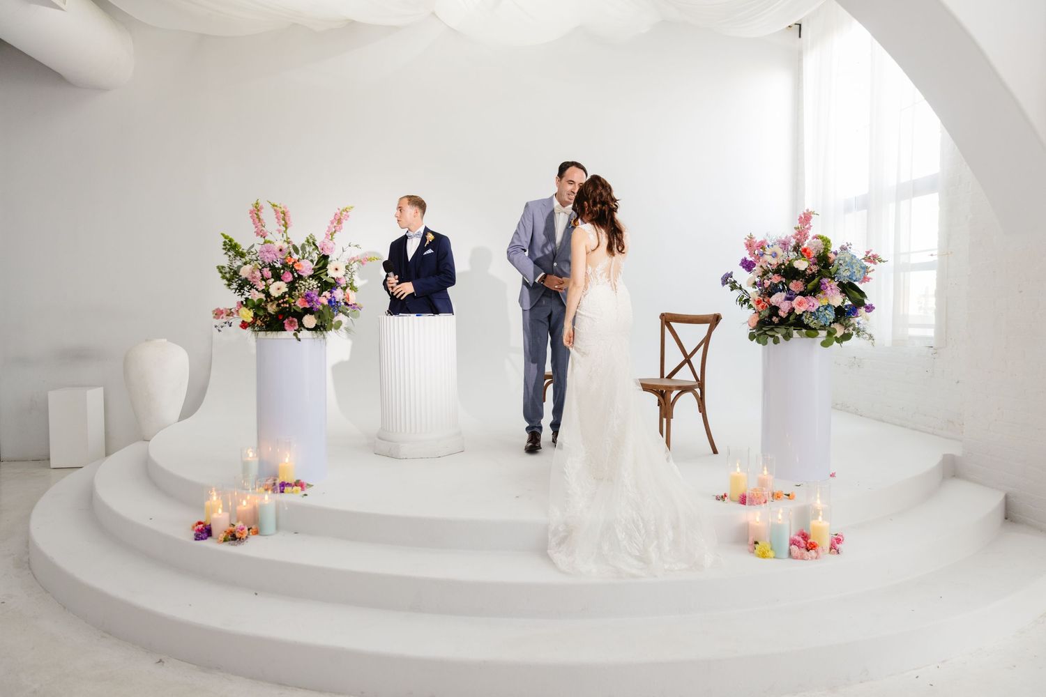 Wedding photoshoot in a minimalist white studio with romantic floral decorations.