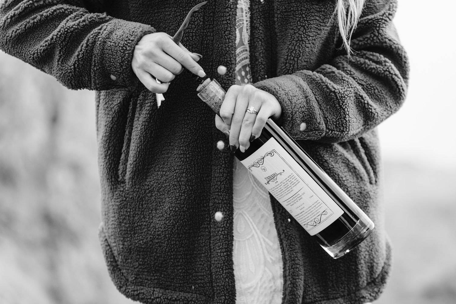 Hands holding bottle of whiskey in black and white photography.