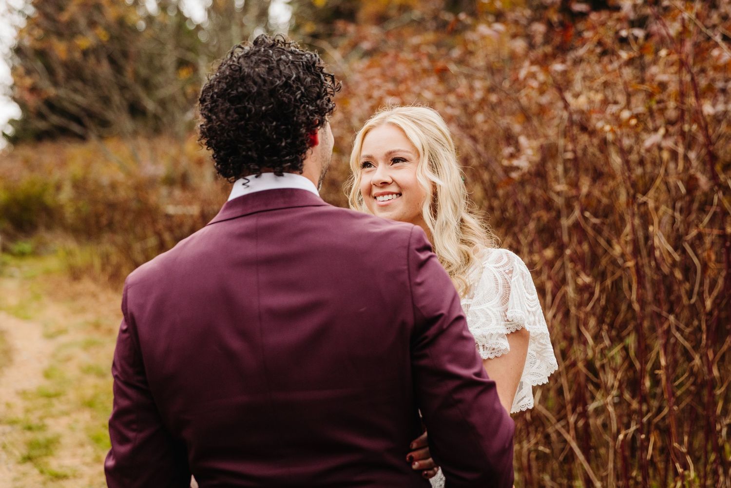 Intimate wedding moment on autumn trail with fall colors in background.