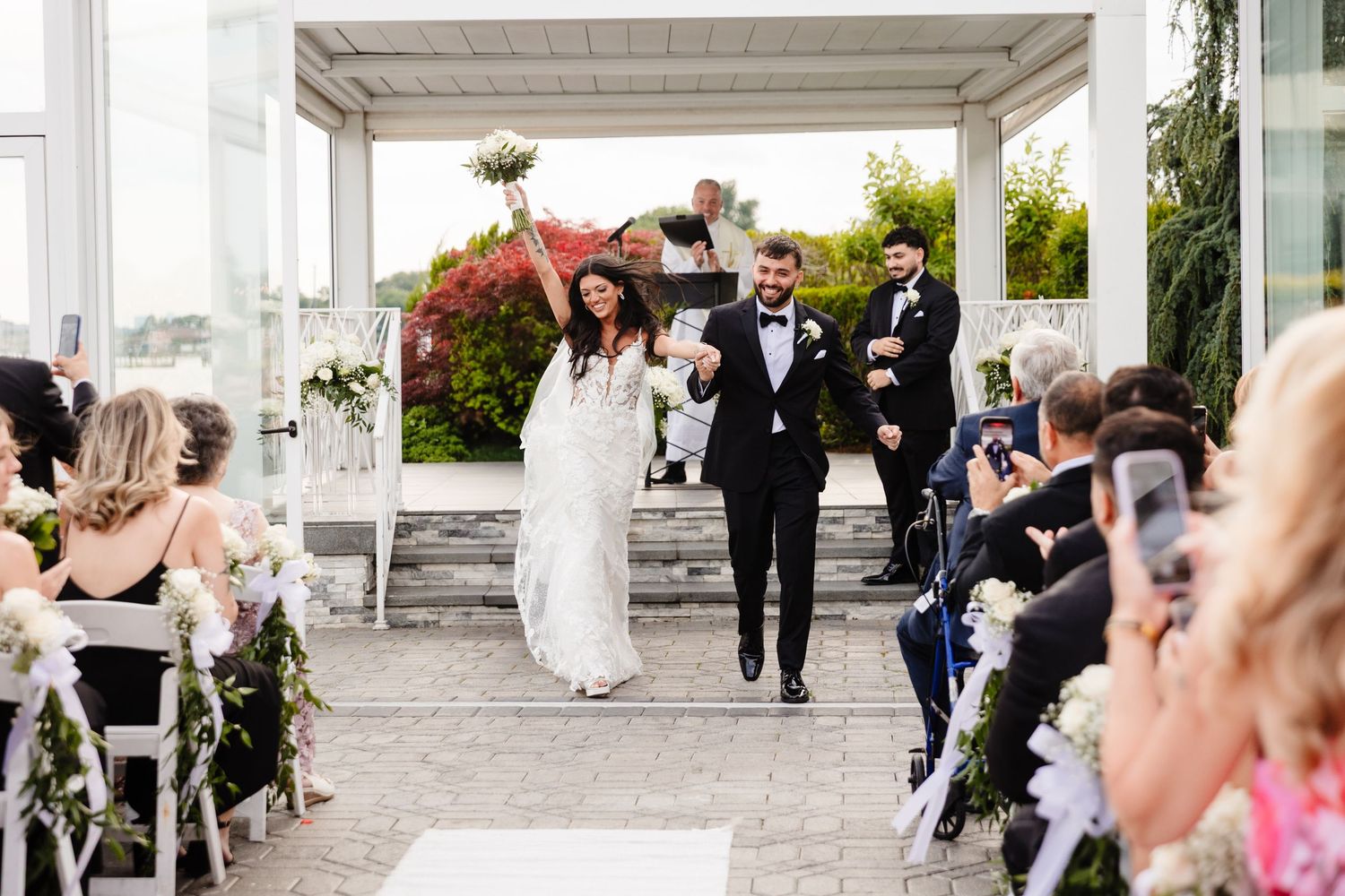 Wedding reception guests mingling on an elegant white columned patio.