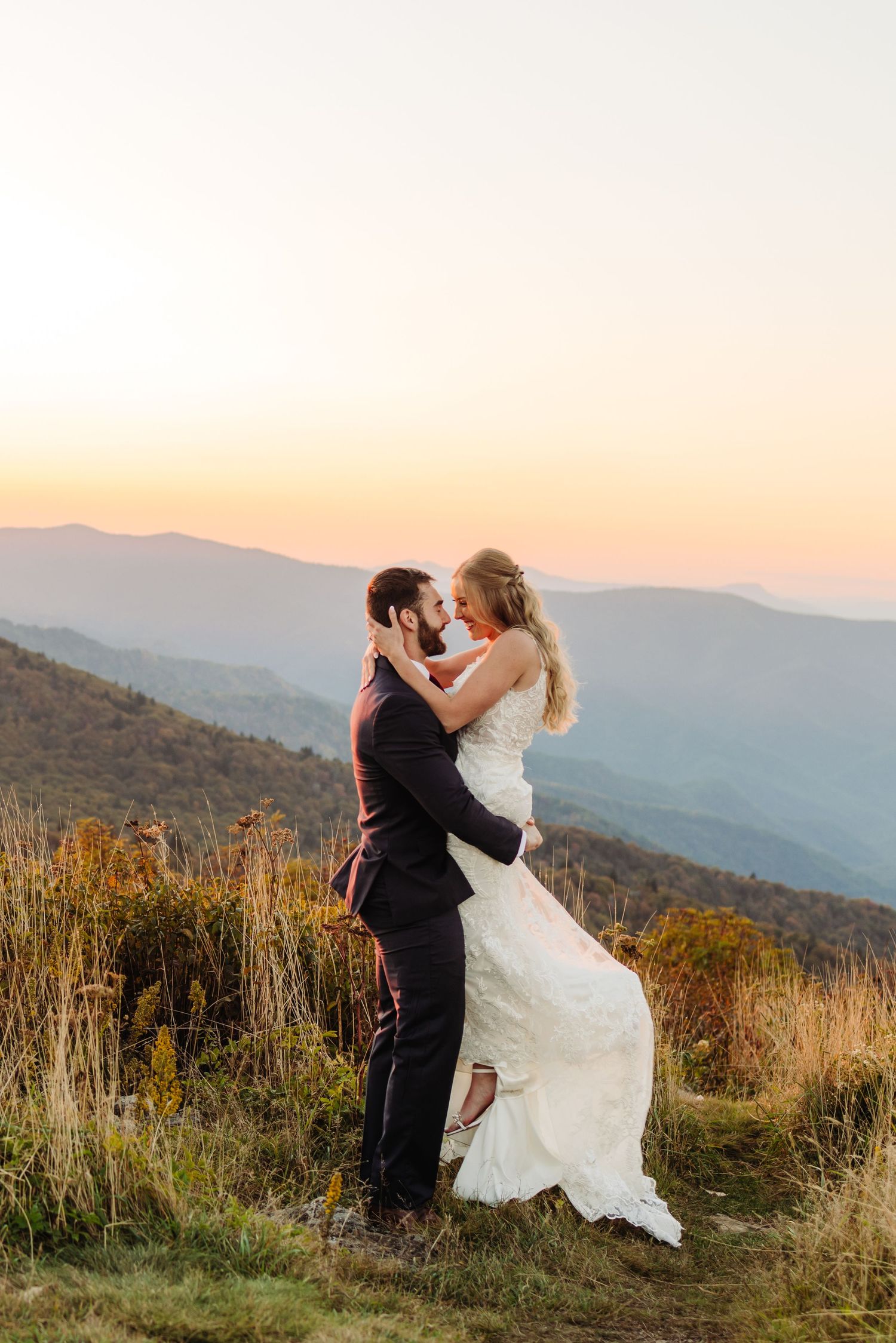 Romantic dance pose on mountain summit during sunset with dramatic landscape views.