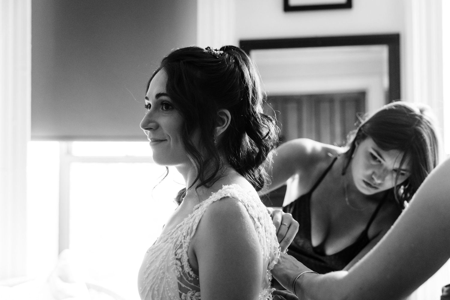 A black and white image showing final wedding dress adjustments being made.