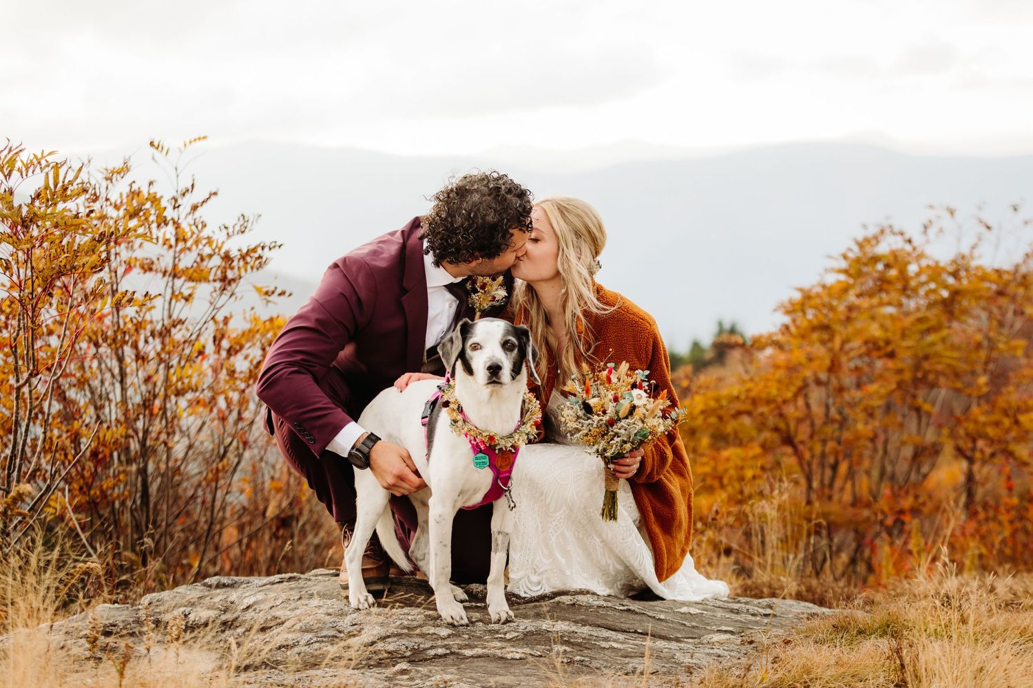 Couple shares intimate moment on autumn mountain ridge with warm fall colors.