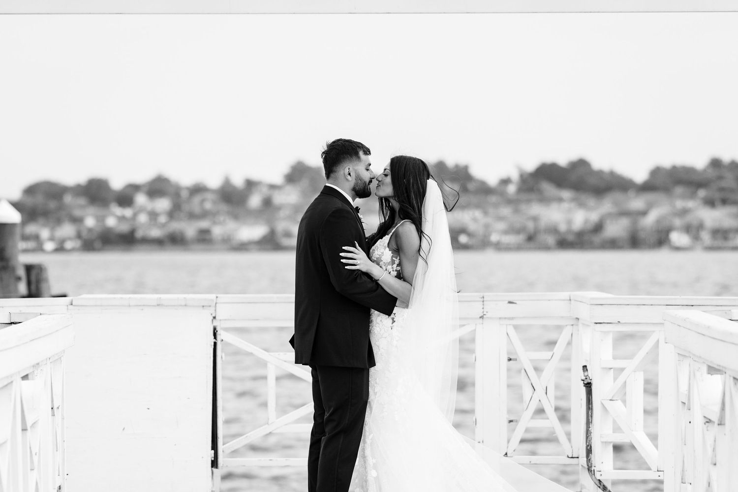 Elegant seaside wedding photography on a classic white pier overlooking the water.